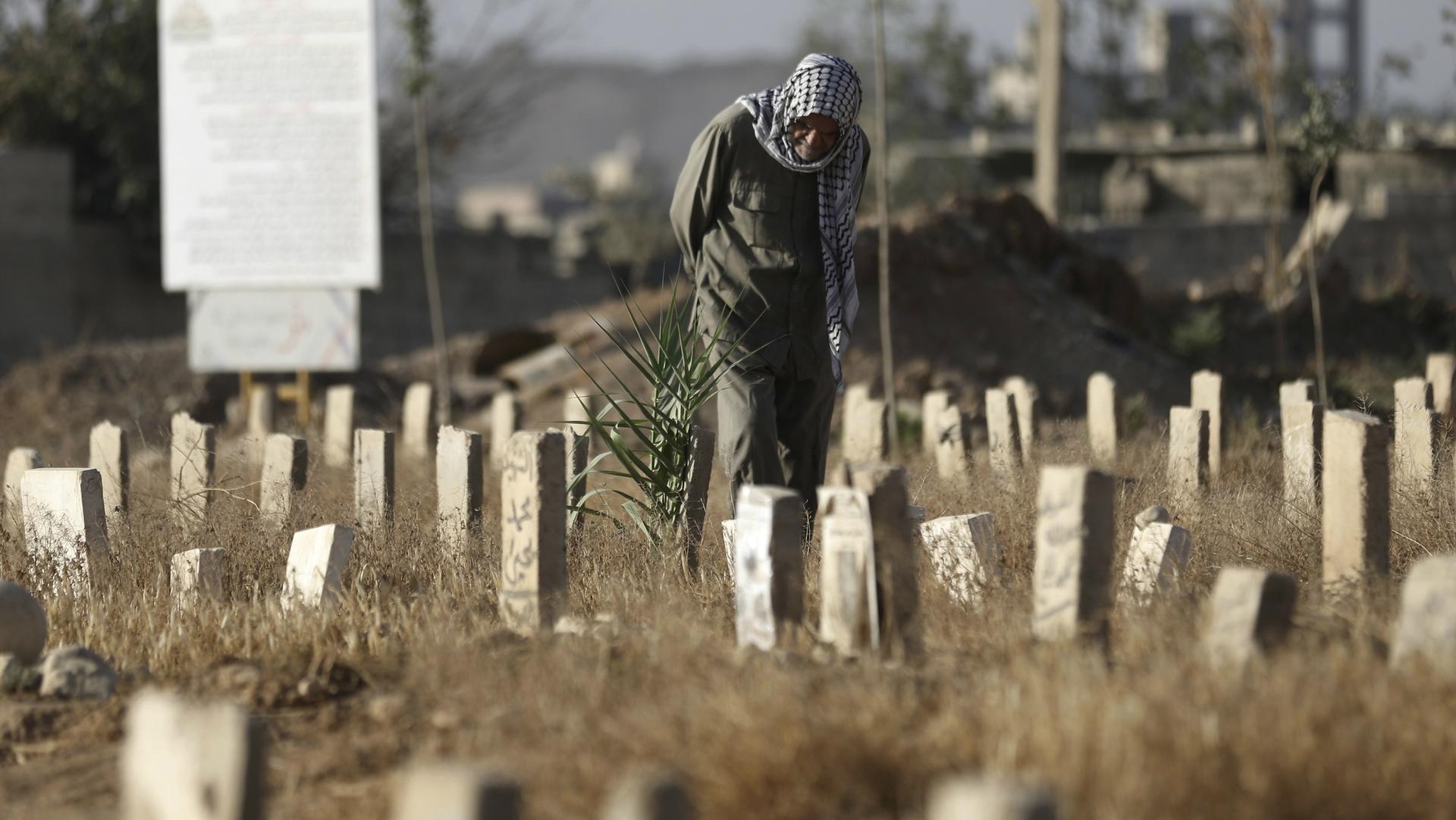 A man visits a cemetery on the first day of Eid al-Adha in Douma, near Damascus, Syria, Sept. 24, 2015.