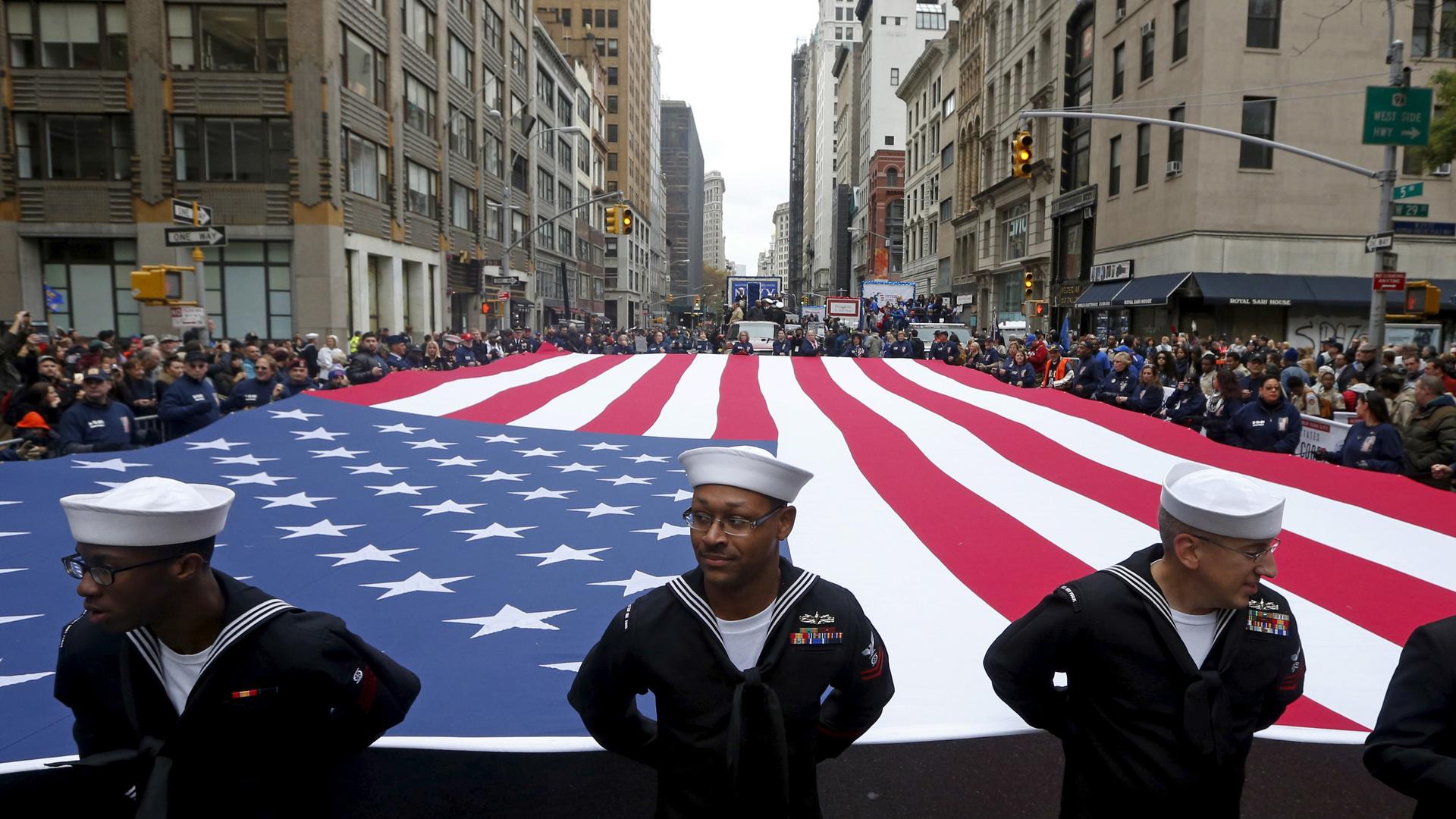Members of the armed forces hold a US flag during the 2015 Veterans Day parade in New York