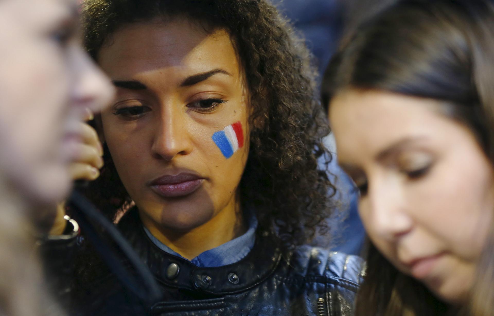 A woman wears the painted colours of France's national flag on her cheek during a candlelight vigil for the victims of the Paris attacks, in Sydney, Australia, November 14, 2015.