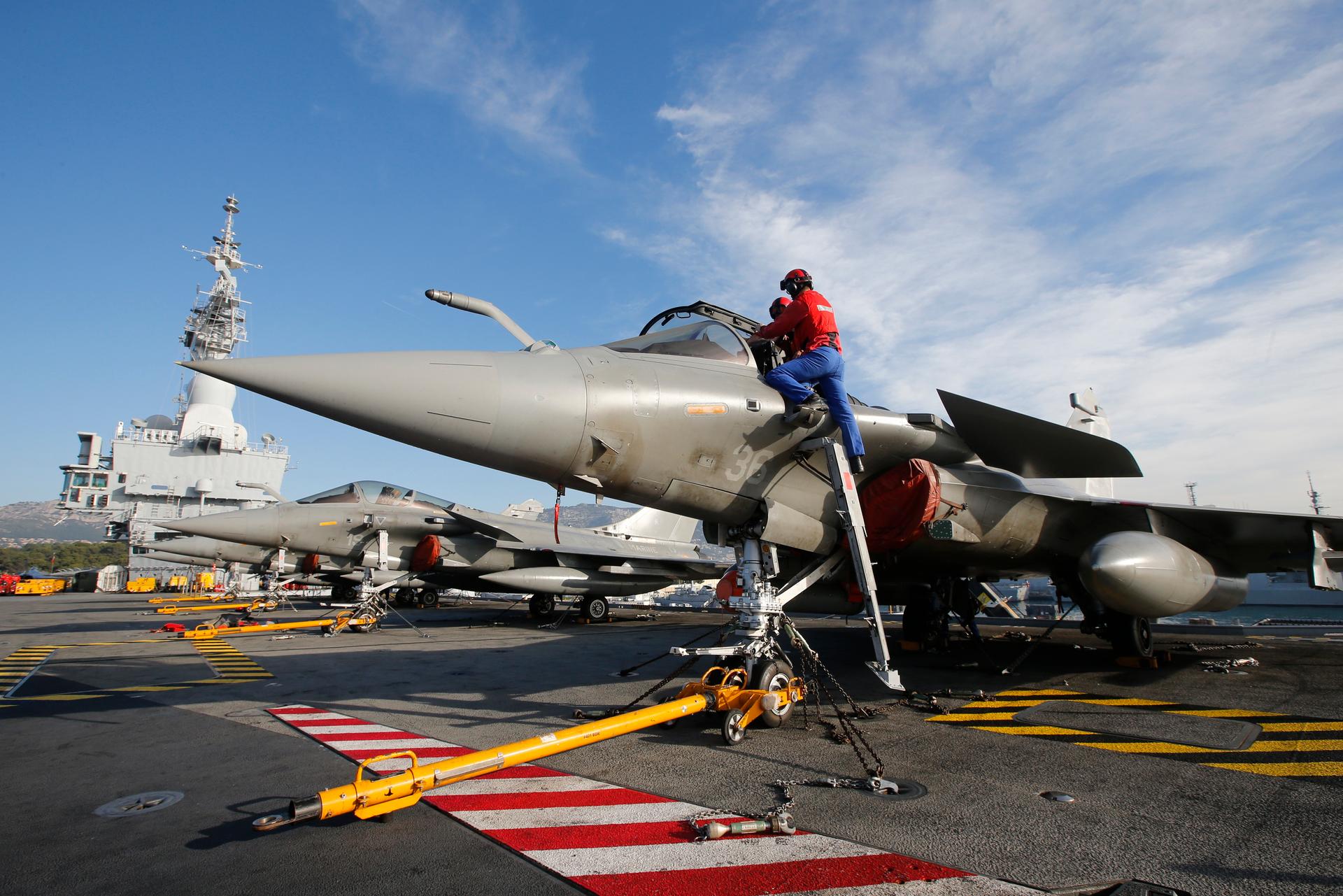 Flight deck crew work on Rafale fighter jets aboard the French nuclear-powered aircraft carrier Charles de Gaulle