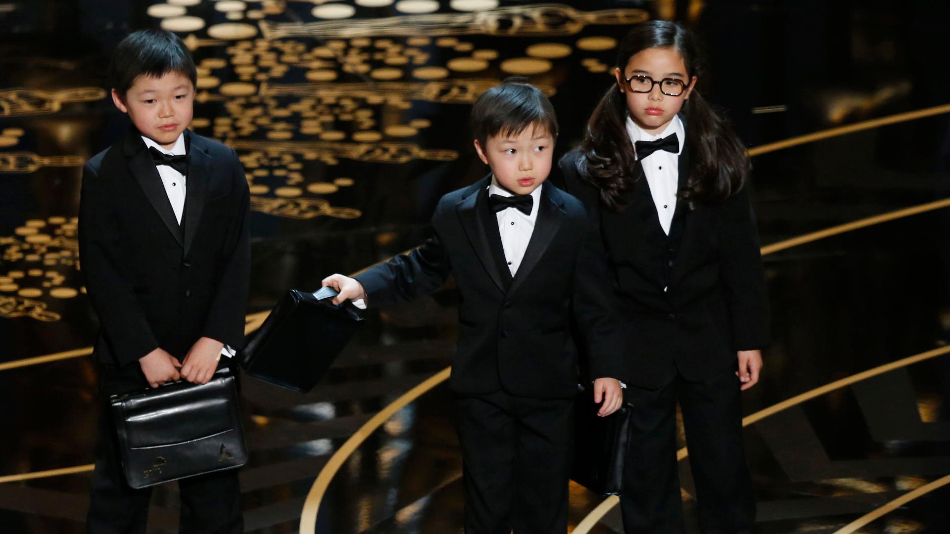 Three children in tuxedos on stage at the Oscars