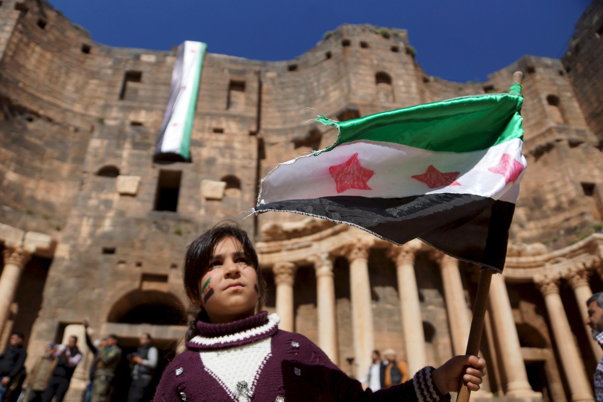 A Syrian girl waves an opposition flag during an anti-government protest inside a 2nd century Roman amphitheater in the historic Syrian southern town of Bosra al-Sham, in Deraa, Syria.