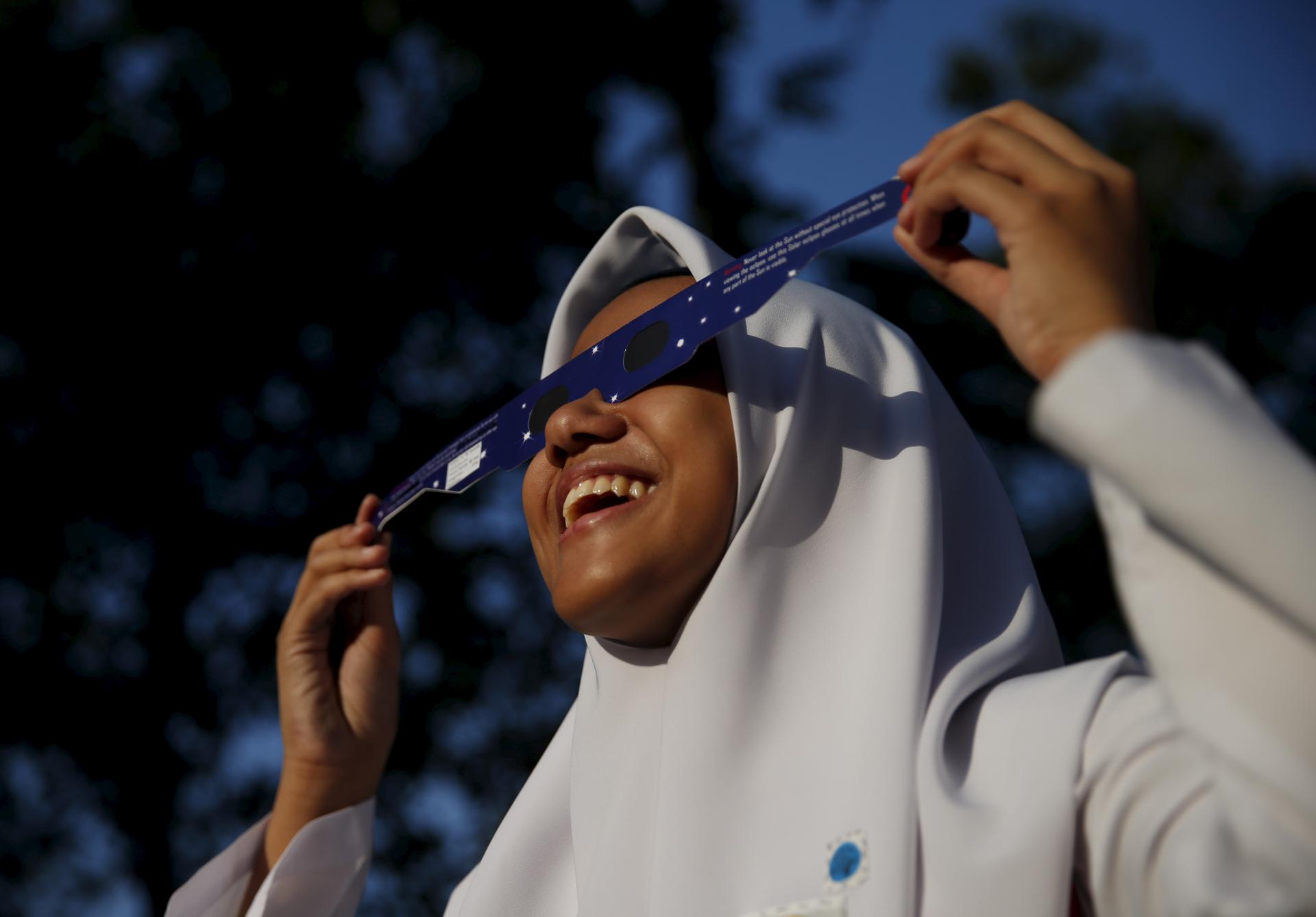 A school girl watches a partial solar eclipse at the Planetarium in Kuala Lumpur, Malaysia, March 9, 2016.