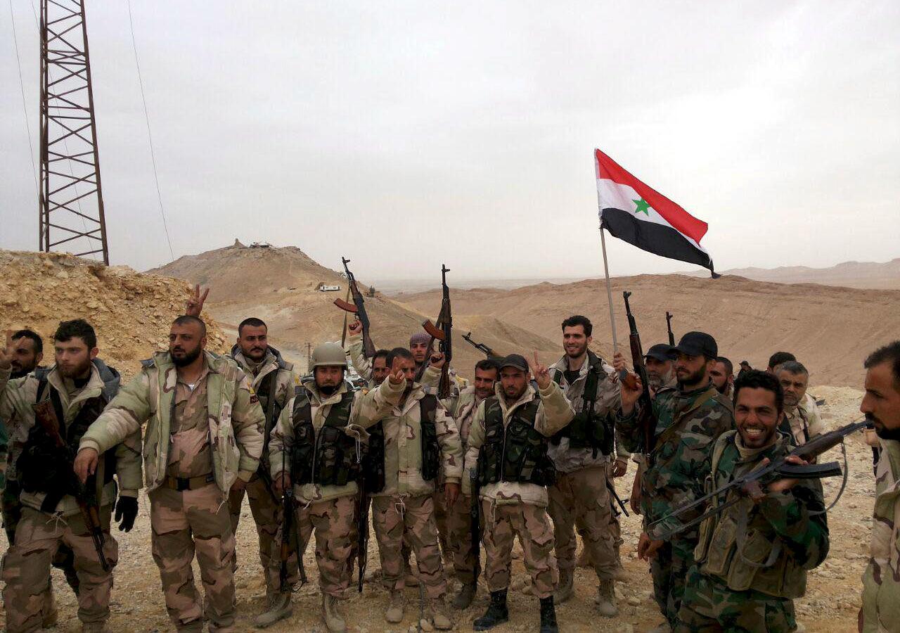 Forces loyal to Syria's President Bashar al-Assad flash victory signs and carry a Syrian national flag on the edge of the historic city of Palmyra in Homs Governorate, in this handout picture provided by SANA on March 26, 2016. 