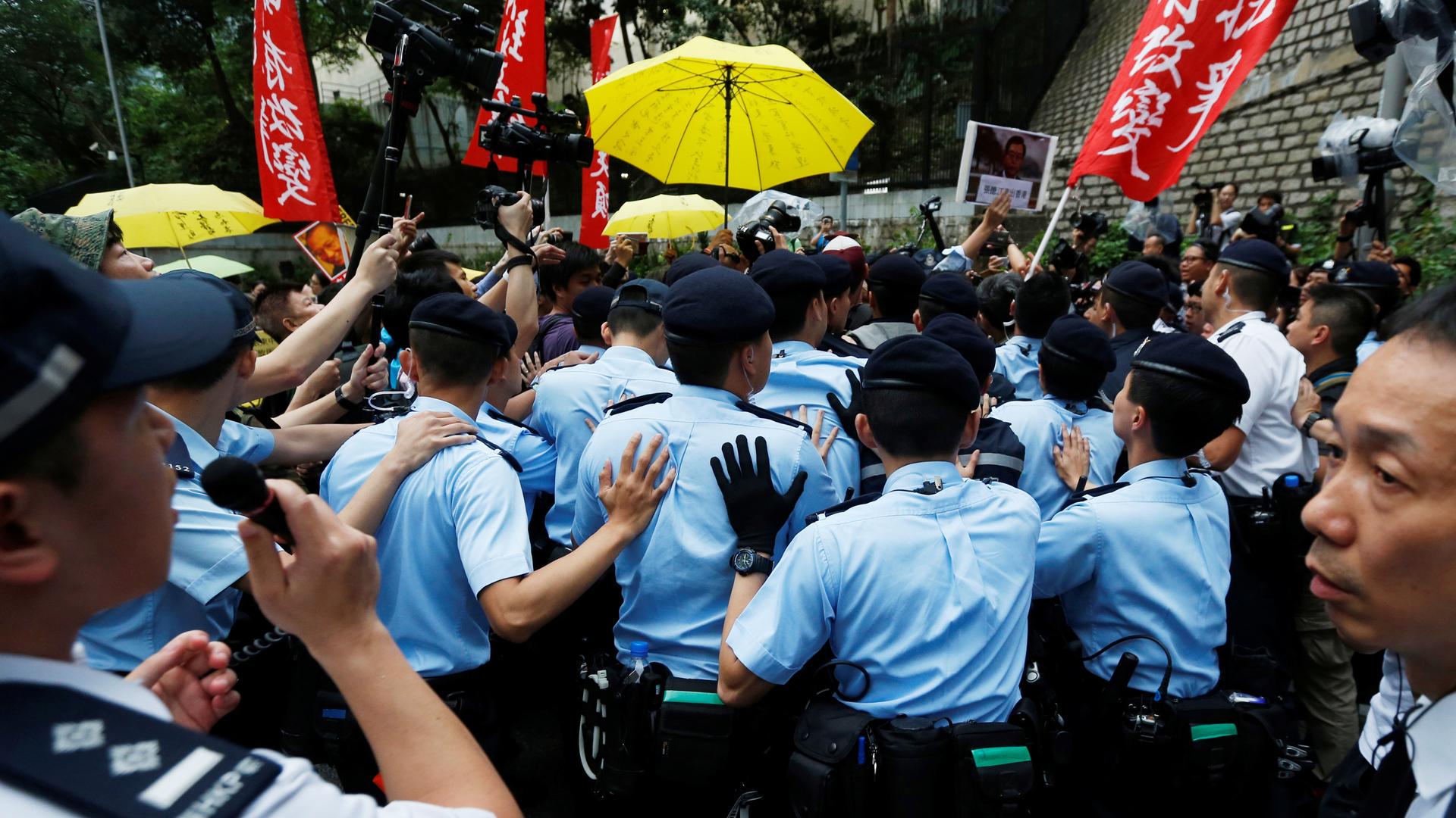 Police officers block protesters during a demonstration in Hong Kong against a visit by a top official from Beijing