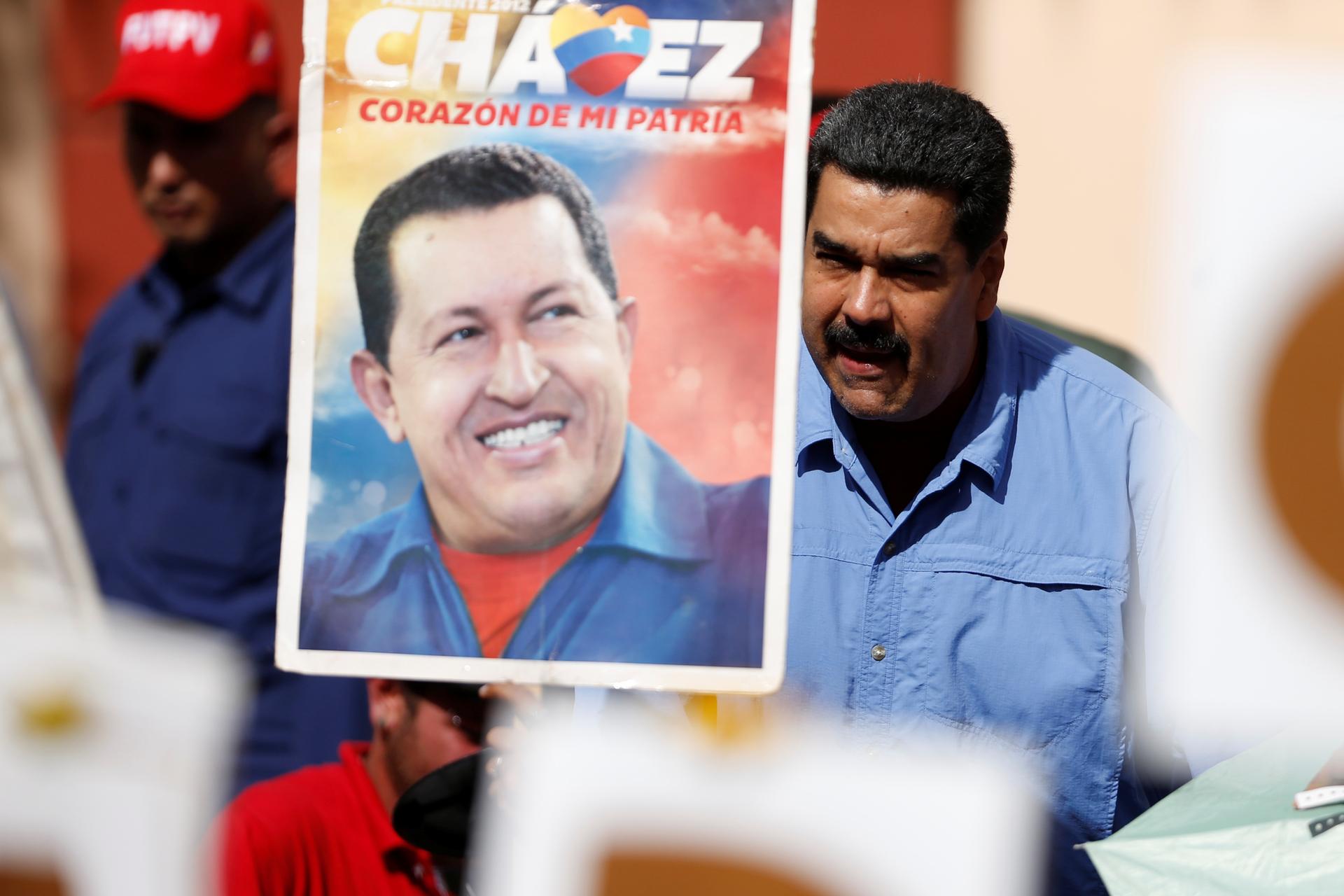 Venezuela's President Nicolas Maduro greets supporters next to a placard with an image of Venezuela's late President Hugo Chavez, at Miraflores Palace in Caracas, Venezuela May 24, 2016.