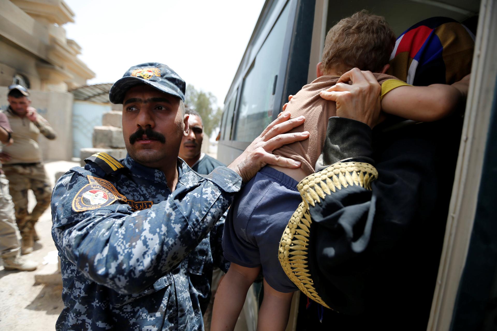 A member of the Iraqi security forces carries a child as he assists civilians, who had fled their homes due to clashes, at Camp Tariq, south of Fallujah, Iraq, June 4, 2016.