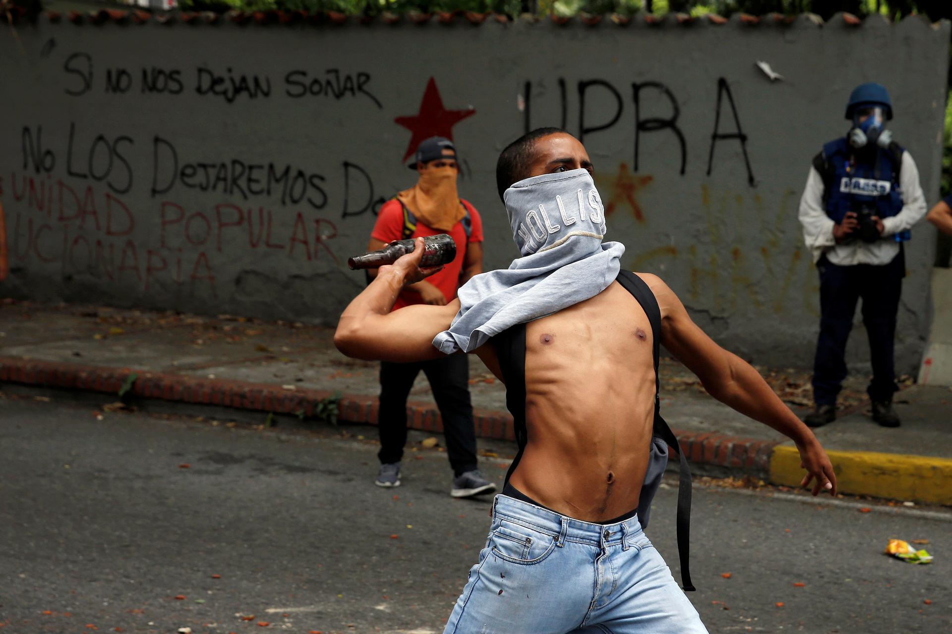 A demonstrator attempts to throw a bottle towards riot police officers during a protest called by university students against Venezuela's government in Caracas, Venezuela, June 9, 2016.