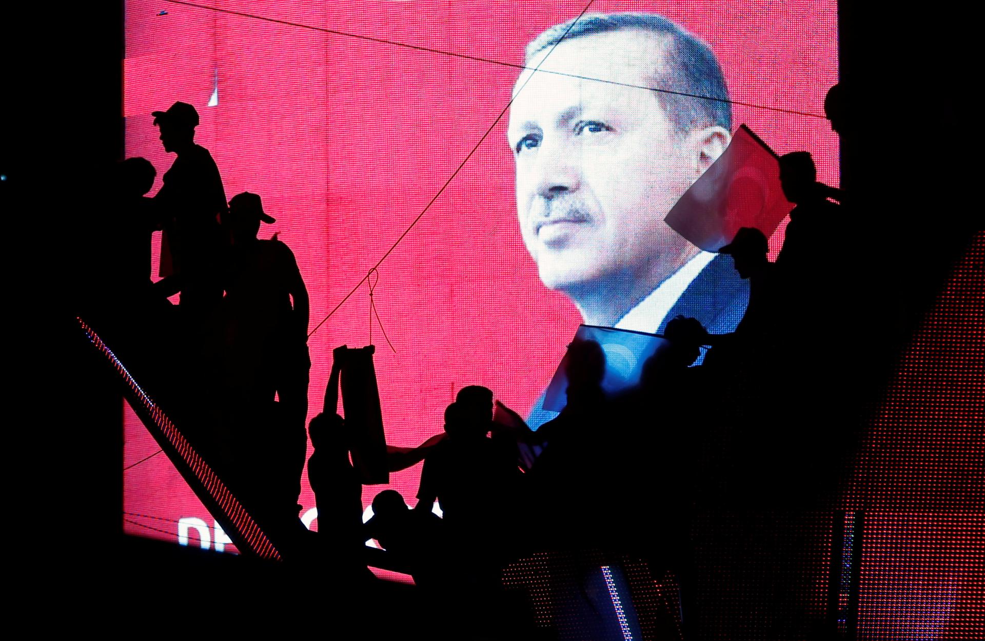 Activists in Turkey are silhouetted against a screen showing President Tayyip Erdogan during a pro-government demonstration in Ankara, Turkey, July 17, 2016.