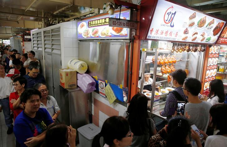 People queue outside hawker Chan Hong Meng's Michelin star awarded stall, for his soya sauce chicken rice and noodle at a food market in Singapore.