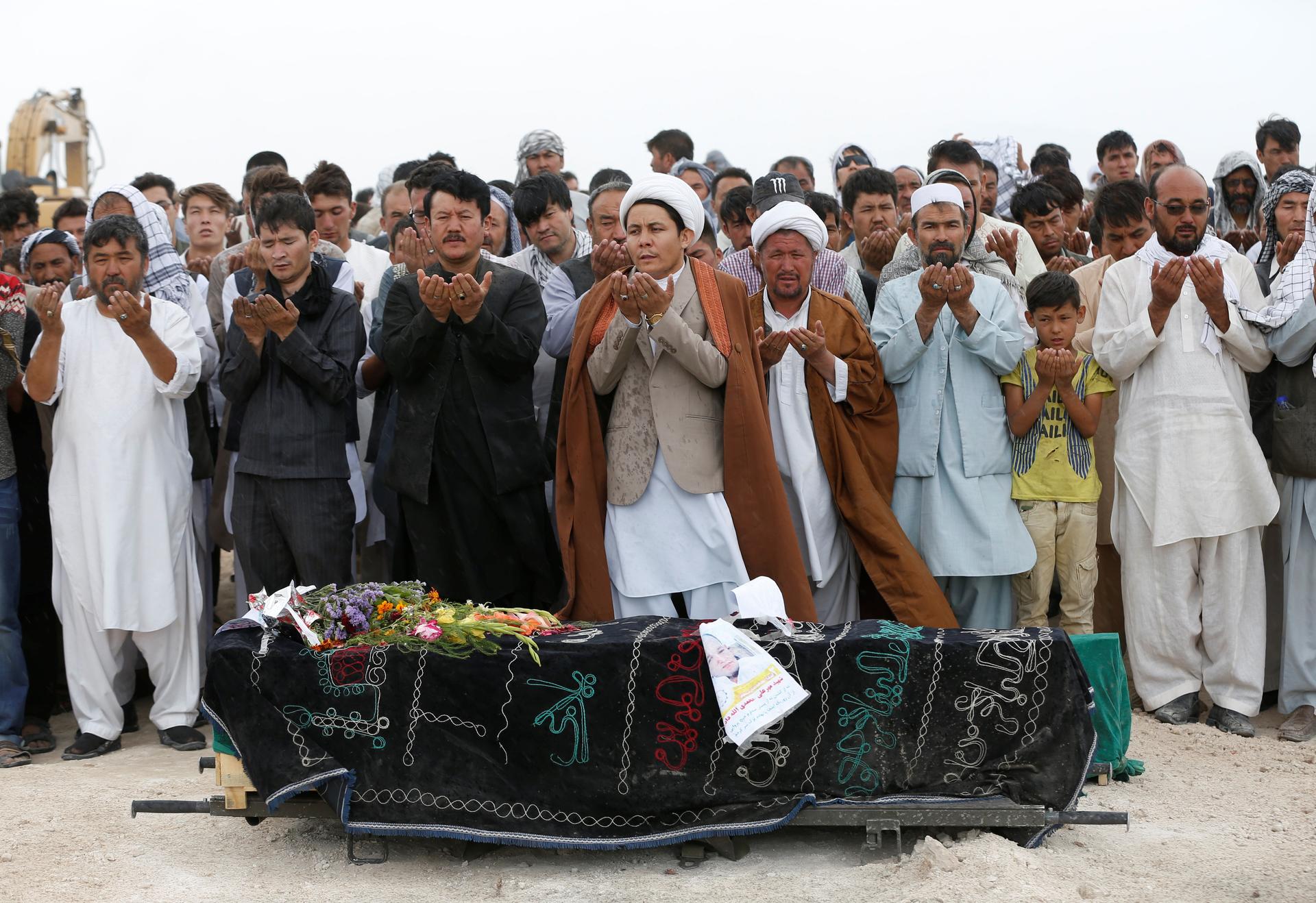 People perform prayers at the funeral for one of the victims of yesterday's suicide attack in Kabul, Afghanistan July 24, 2016.