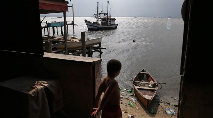 A boy throws a plastic bottle into Guanabara Bay in Rio de Janeiro on Aug. 7.