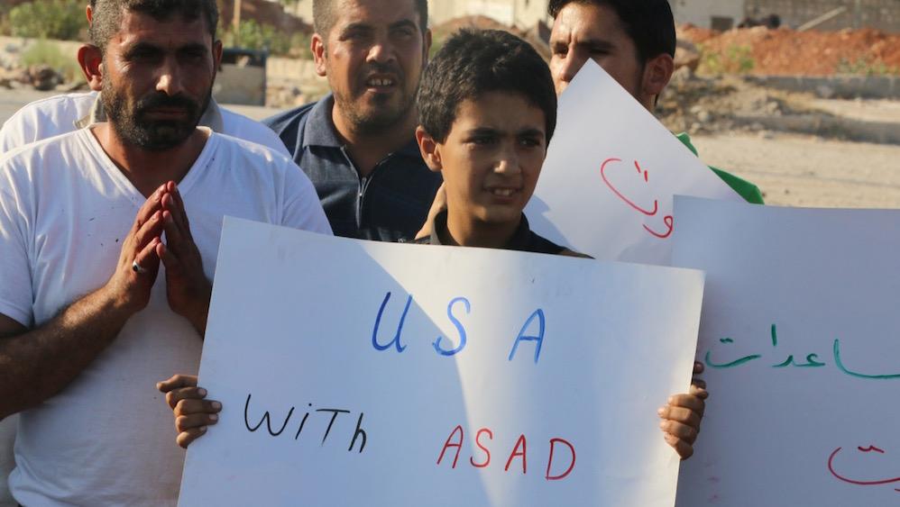 After a US-Russia brokered ceasefire, a boy carries a placard during a demonstration against forces loyal to Syrian President Bashar al-Assad and calling for aid to reach Aleppo near Castello road in Aleppo, Syria, Sept. 14.