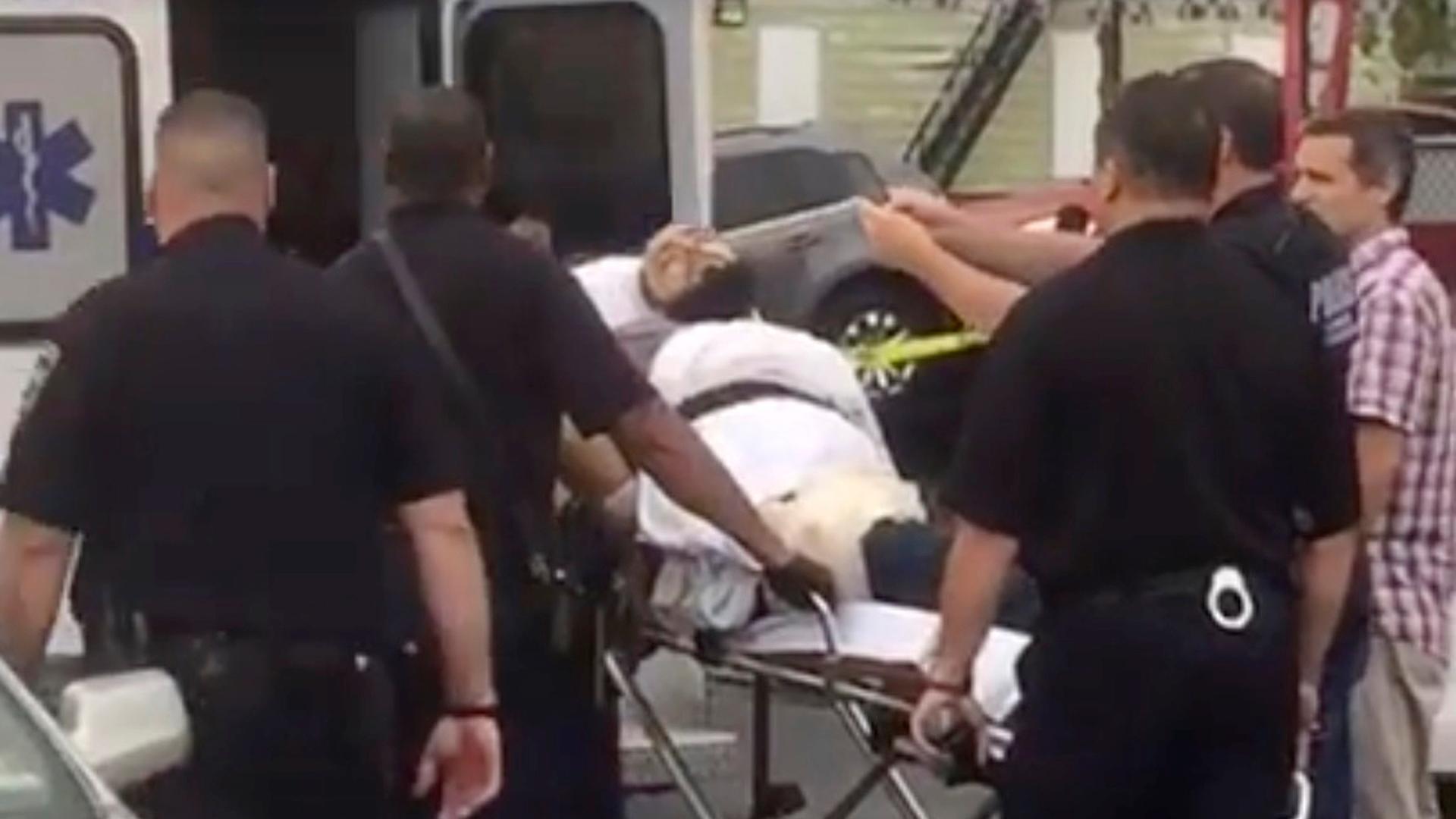 A policeman takes a photo of a man they identify as Ahmad Khan Rahami, who is wanted for questioning in connection with an explosion in New York City, as he is placed into an ambulance in Linden, New Jersey, in this still image taken from video. 