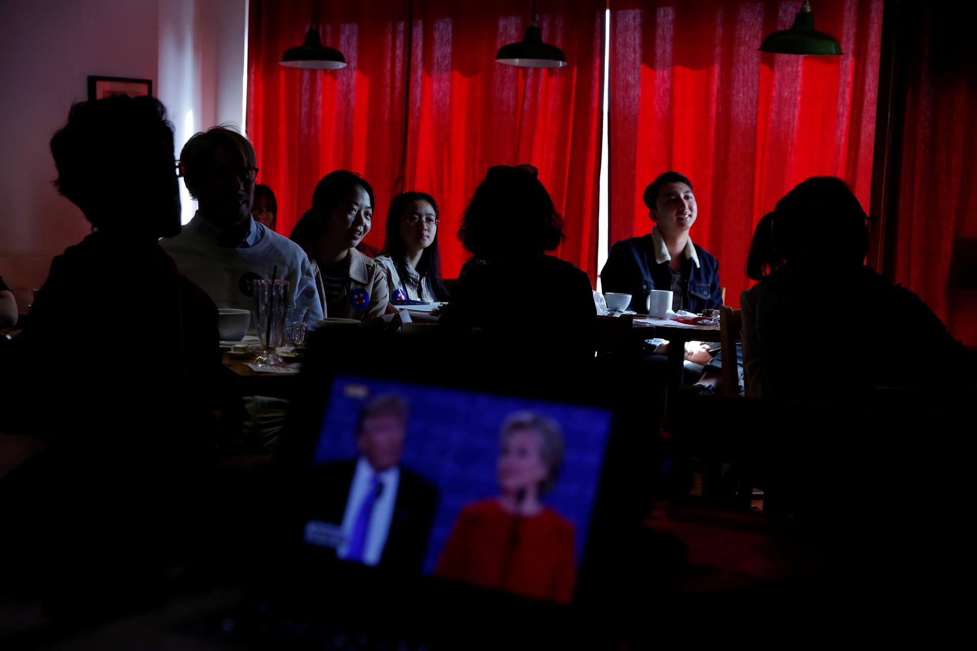 People watch a direct broadcast of the first U.S. presidential debate between Republican U.S. presidential nominee Donald Trump and Democratic U.S. presidential nominee Hillary Clinton at a cafe in Beijing, China on September 27, 2016.