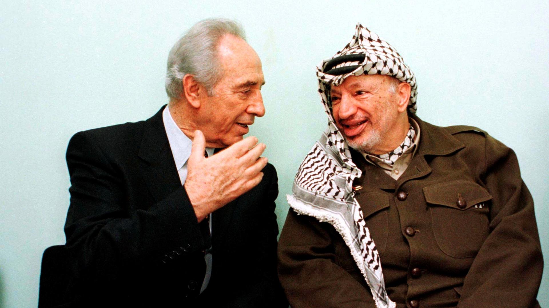Former Isareli Prime Minister Shimon Peres (left) chats with Palestinian President Yasser Arafat while attending the inauguration ceremony of a park in memory of the former Norwegian Foreign Minister Jorgen Holst in the Gaza Strip in this October 13, 1998