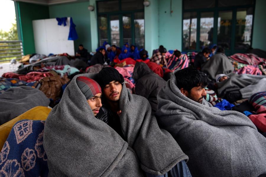Refugees and migrants try to warm themselves as they take a break at a gas station before abandoning their trek to the Hungarian border, in the town of Indjija, Serbia on Oct. 5.