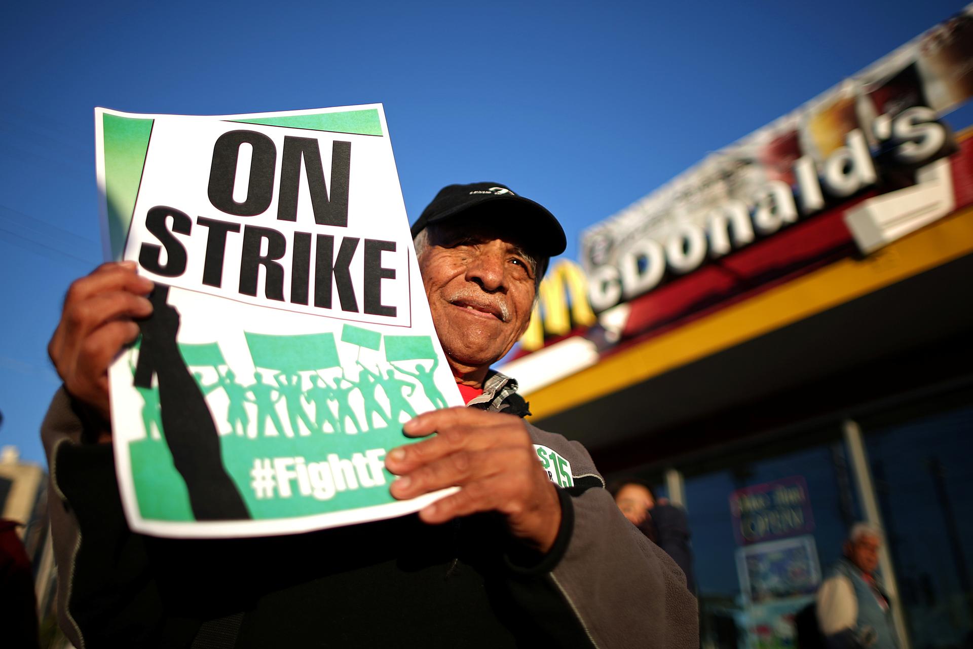 Man holding up protest sign in front of a McDonald's