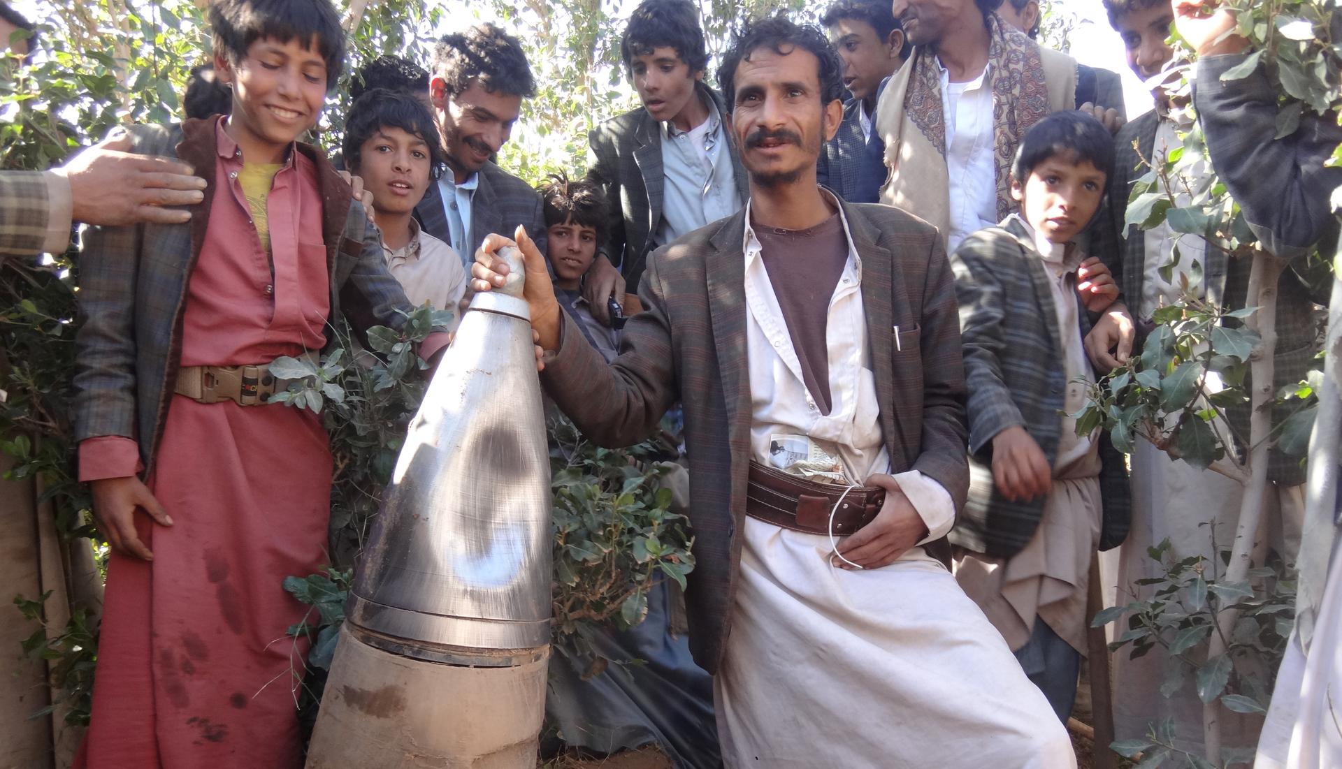 Yemenis pose for a picture next to a part of a missile they say was dropped during a Saudi-led air strike near the northwestern city of Saada, Yemen