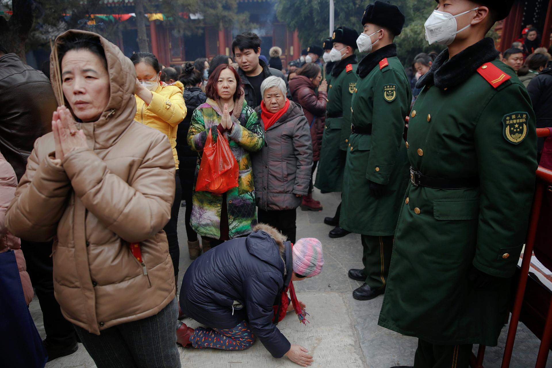 Women pray in front of paramilitary policemen at Yonghegong Lama Temple on the first day of the Lunar New Year of the Rooster in Beijing, China. 