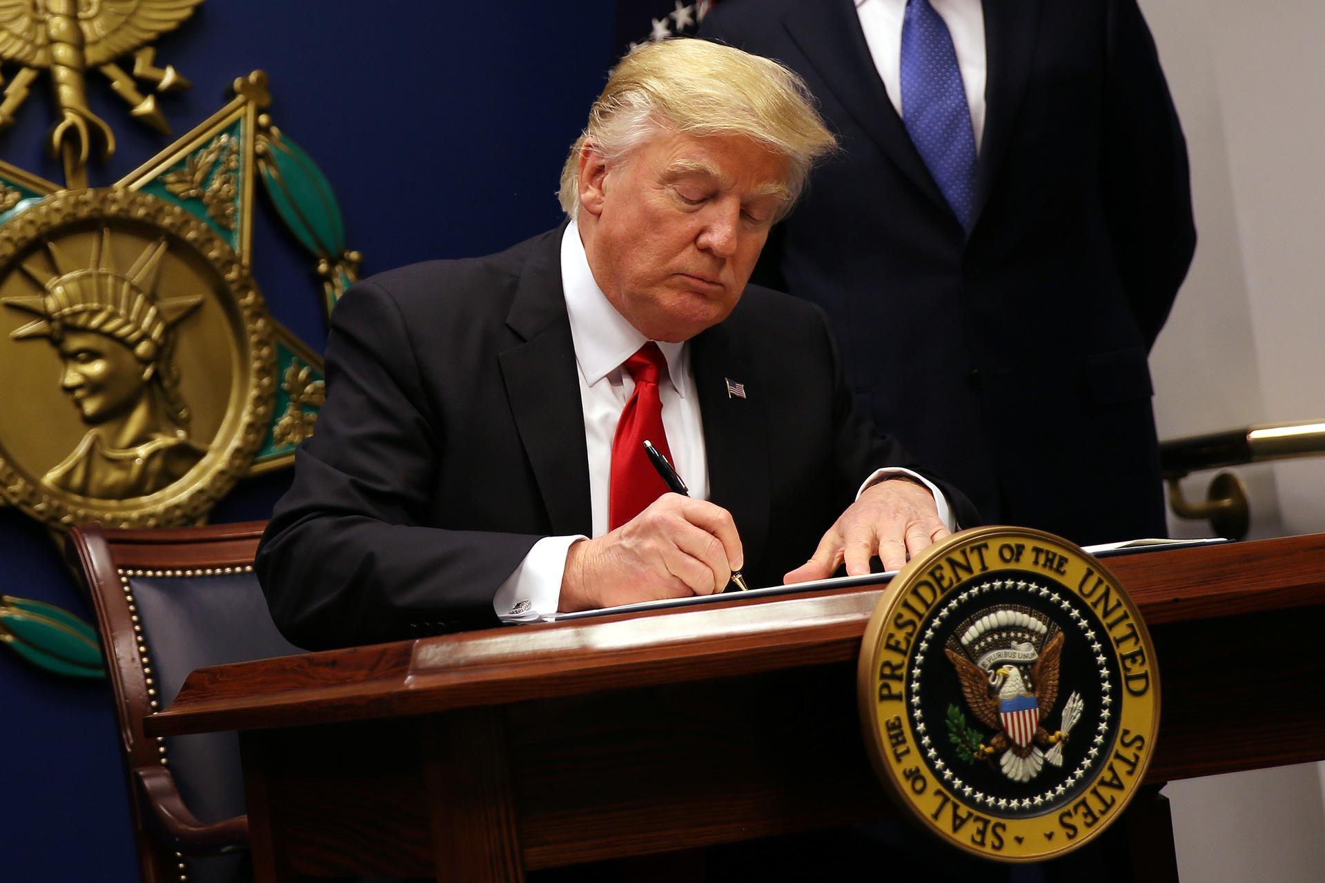 President Donald Trump signs an executive order to impose tighter vetting of travelers entering the United States, at the Pentagon in Washington, D.C.