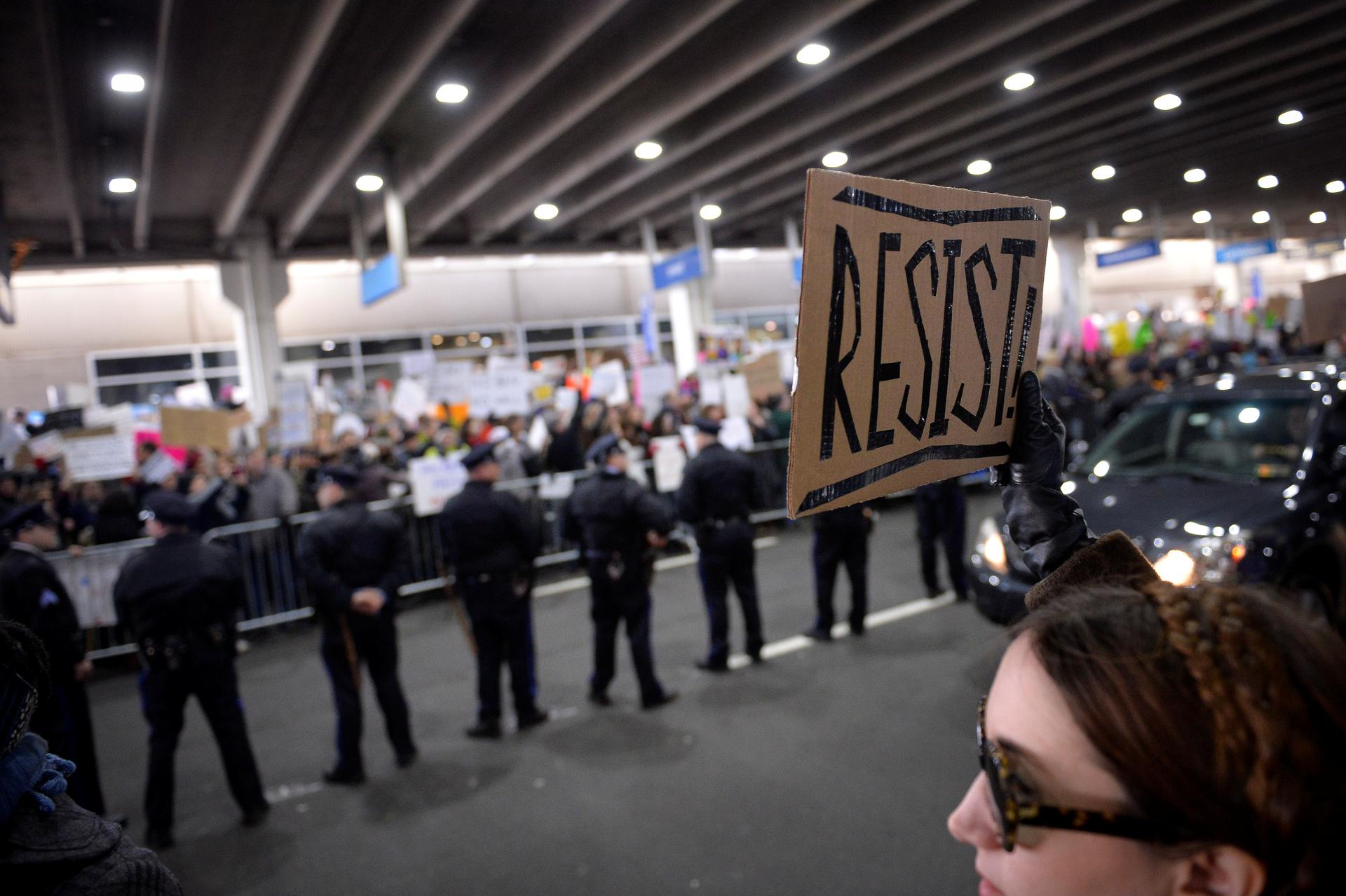 A demonstrator holds a "resist" sign during anti-Donald Trump travel ban protests outside Philadelphia International Airport in Philadelphia, Pennsylvania, U.S., January 29, 2017.