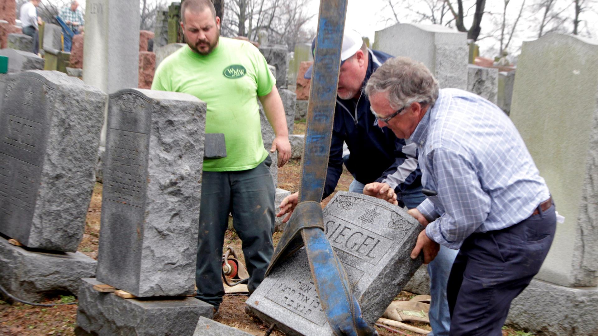 Spencer Pensoneau, Ron Klump and Philip Weiss (left to right), of Weiss and Rosenbloom Monument company, work to right toppled Jewish headstones after a weekend vandalism attack on Chesed Shel Emeth Cemetery in University City, a suburb of St Louis, Misso