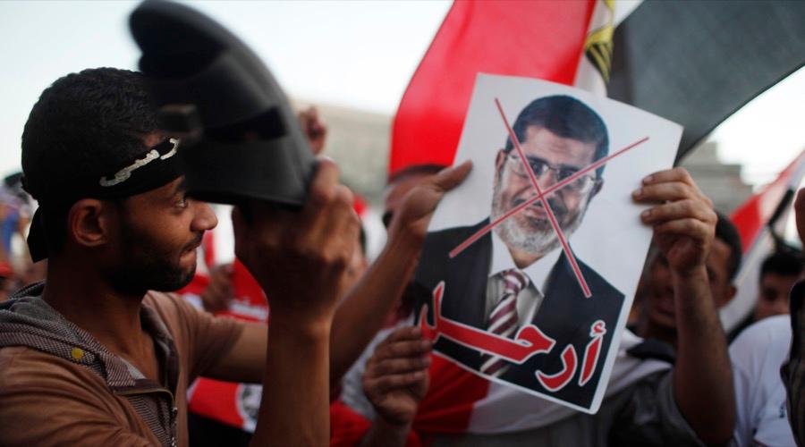 A protester uses his sandal to beat a picture of Egypt's then-President Mohammed Morsi in Tahrir square in Cairo on June 28, 2013.