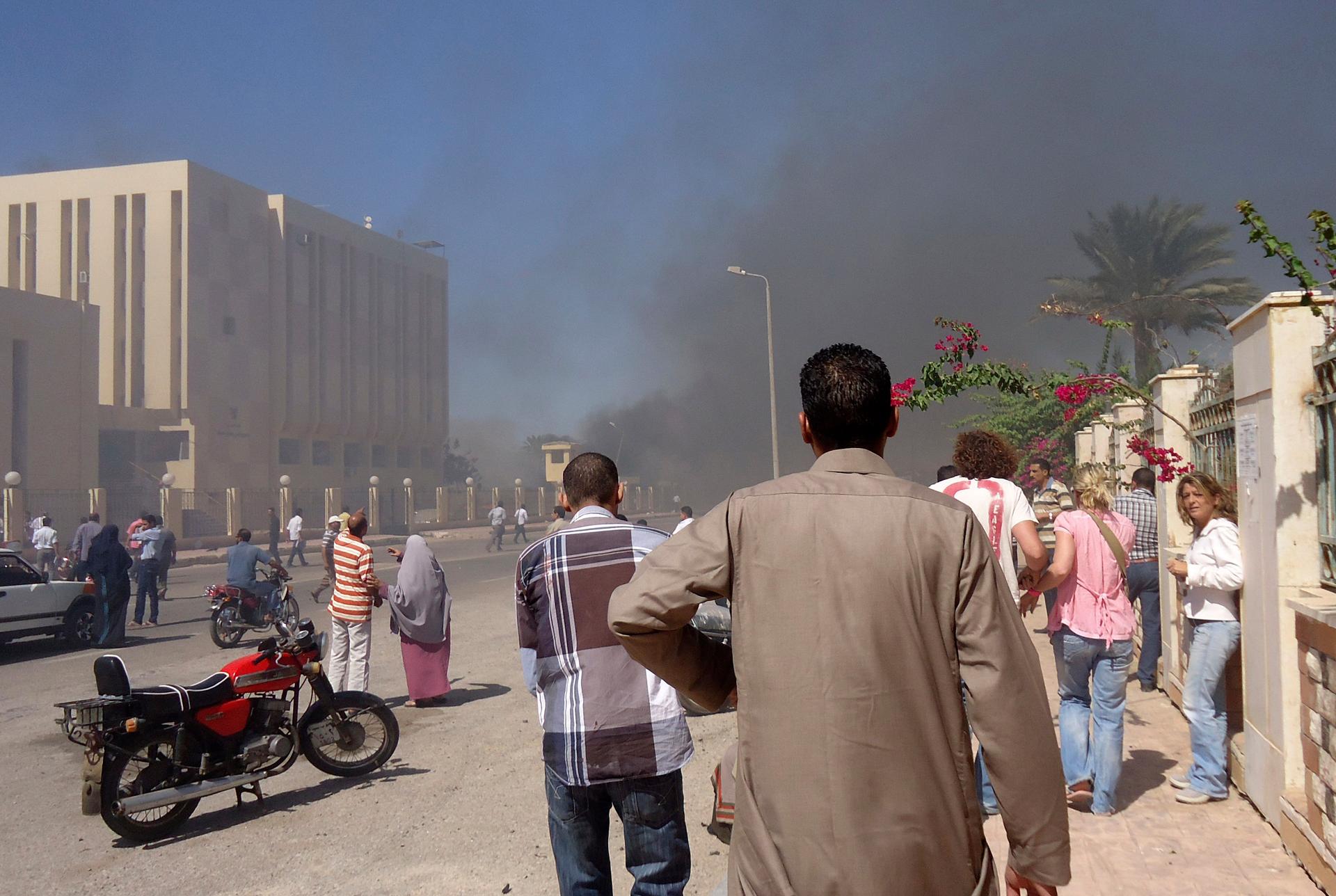 Residents and tourists watch as smoke rises from a state security building in the Sinai after a car bomb blast. Medical sources said three were killed and 48 injured in the attack.
