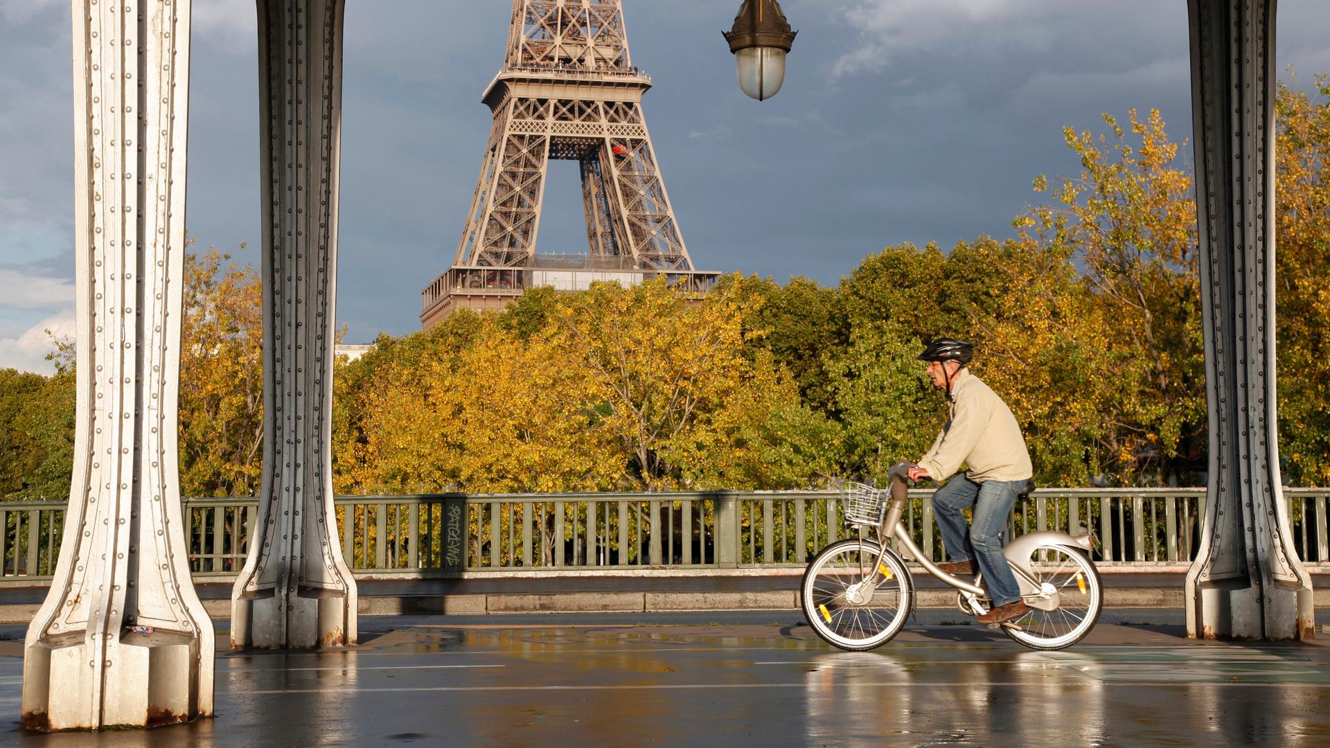 A man rides a Velib self-service public bicycle under an elevated metro line near the the Eiffel Tower after a brief rain shower in Paris October 26, 2013. 