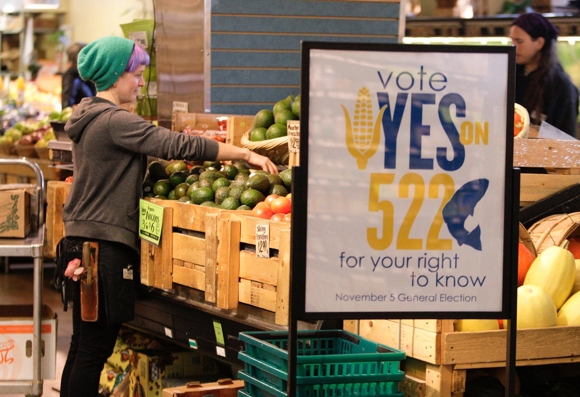 An employee at a Seattle co-op stocks produce near a sign supporting a 2013 ballot initiative in Washington state that would have required labeling of GMO foods. The initiative failed, with record amounts of money spent to defeat it.
