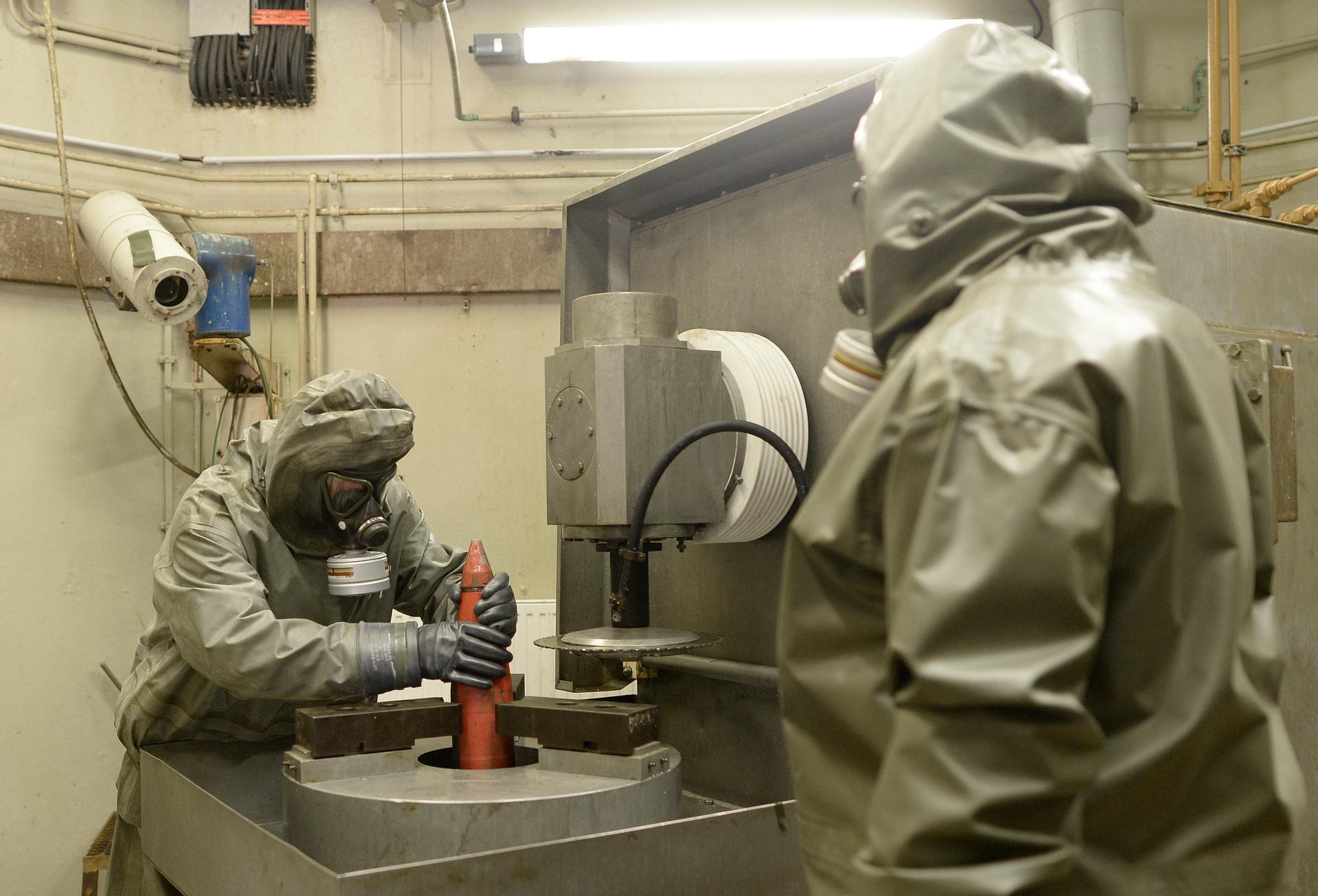 Workers dressed in protective clothes hold a mock chemical World War Two grenade during a demonstration