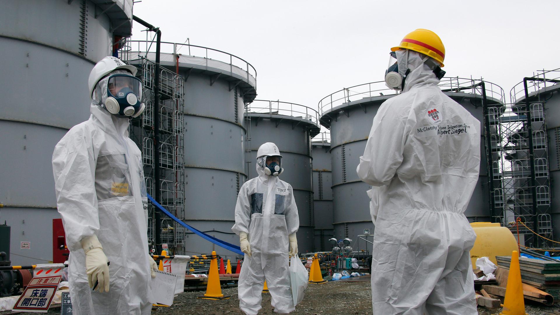 A Tokyo Electric Power Corp (TEPCO) official and journalists wearing protective equipment stand near storage tanks for radioactive water at Japan's tsunami-crippled Fukushima Daiichi nuclear power plant in November, 2013. A team of Japanese scientists say