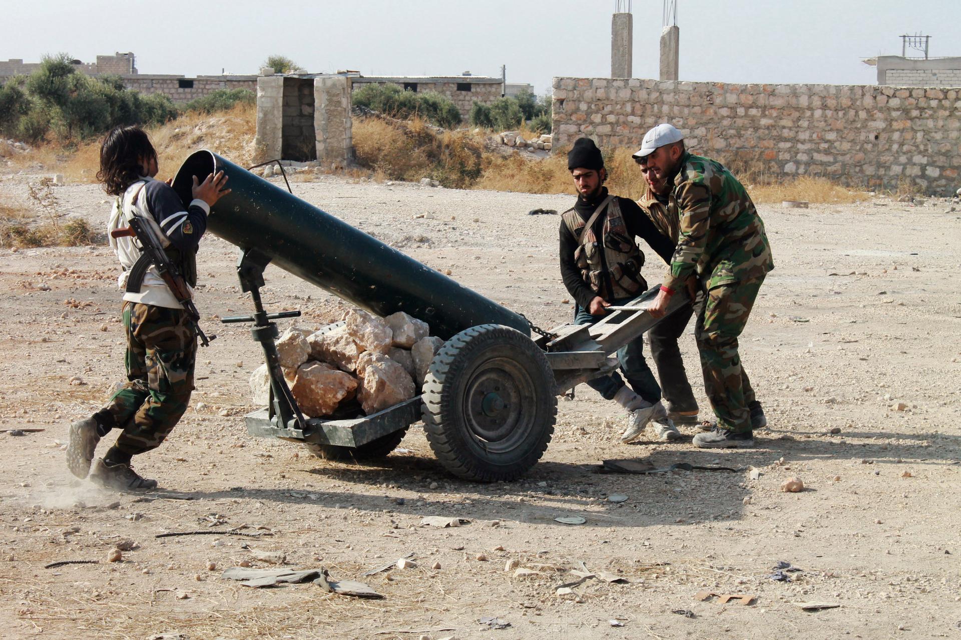 Free Syrian Army fighters prepare a locally-made launcher beside Aleppo International Airport.