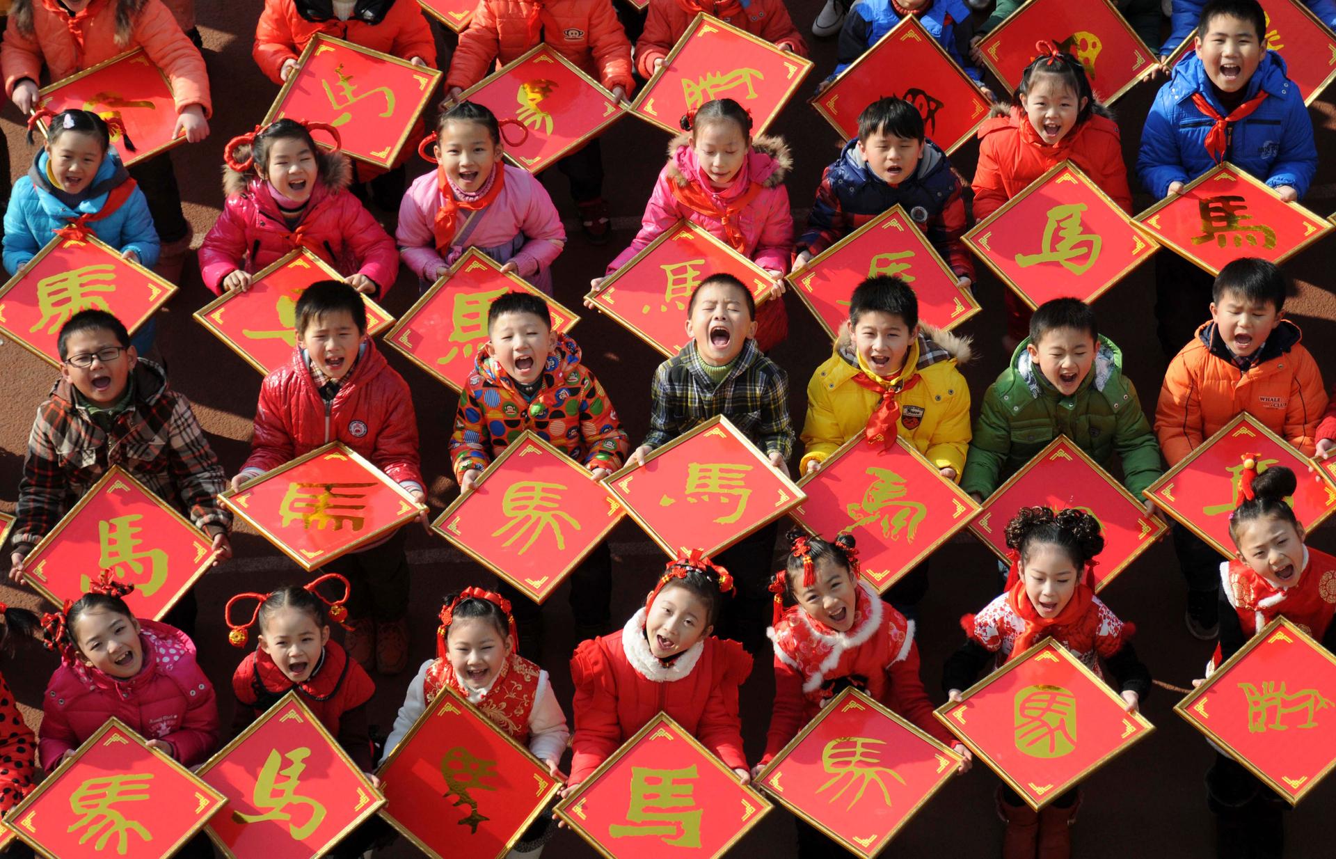 Children pose with their paper-cut works of the Chinese character for "horse", ahead of the Year of the Horse in Chinese zodiac, at a primary school in Jiujiang, Jiangxi province, December 31, 2013.