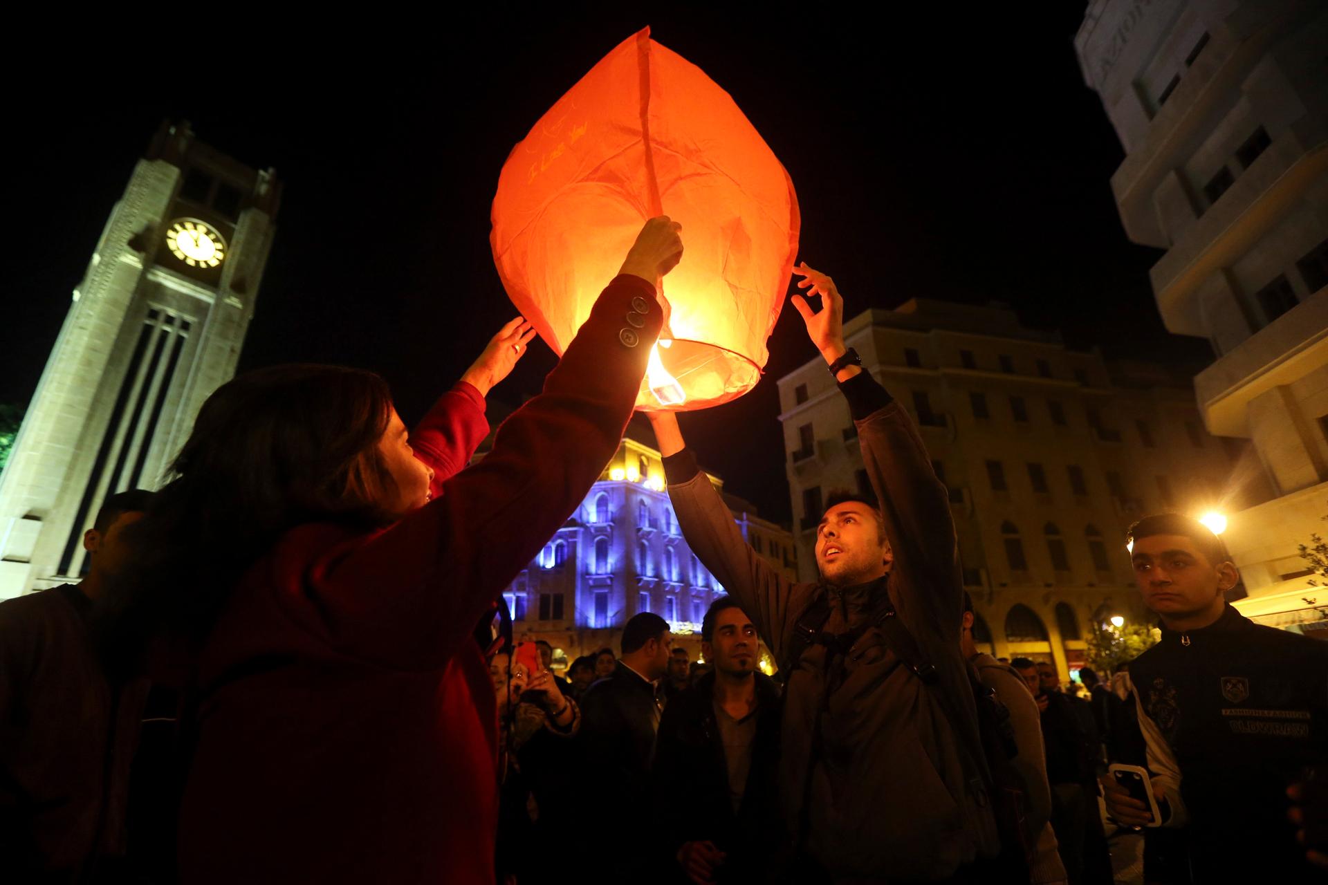 Beirut residents light a lantern during New Year's celebrations at Star Square