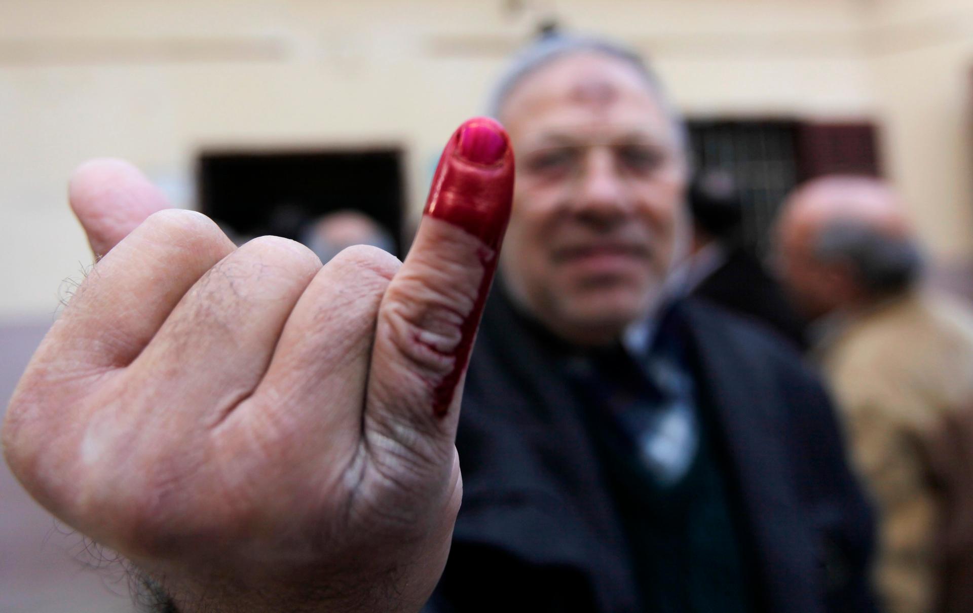 An Egyptian man shows his ink-stained finger after voting in Cairo in the referendum on a new constitution.
