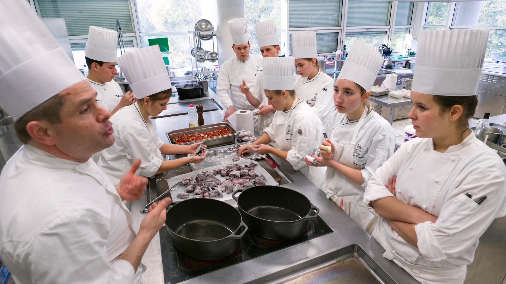 Students prepare food during a class by French chef Eric Cros (left) at the Institut Paul Bocuse.