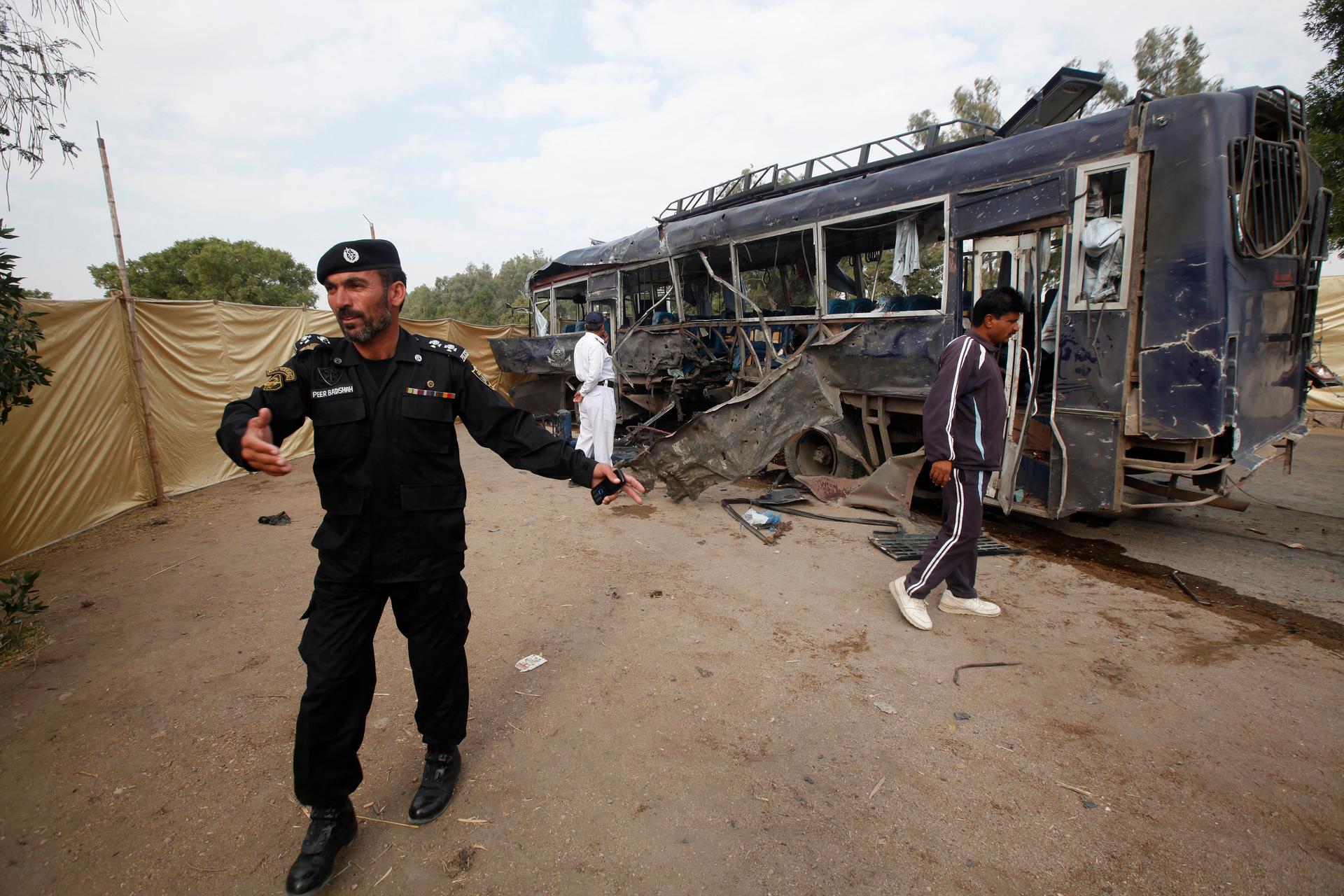 A security official prevents members of the media from approaching a damaged police bus at the site of an explosion in Karachi targeting policemen on February 13, 2014. 