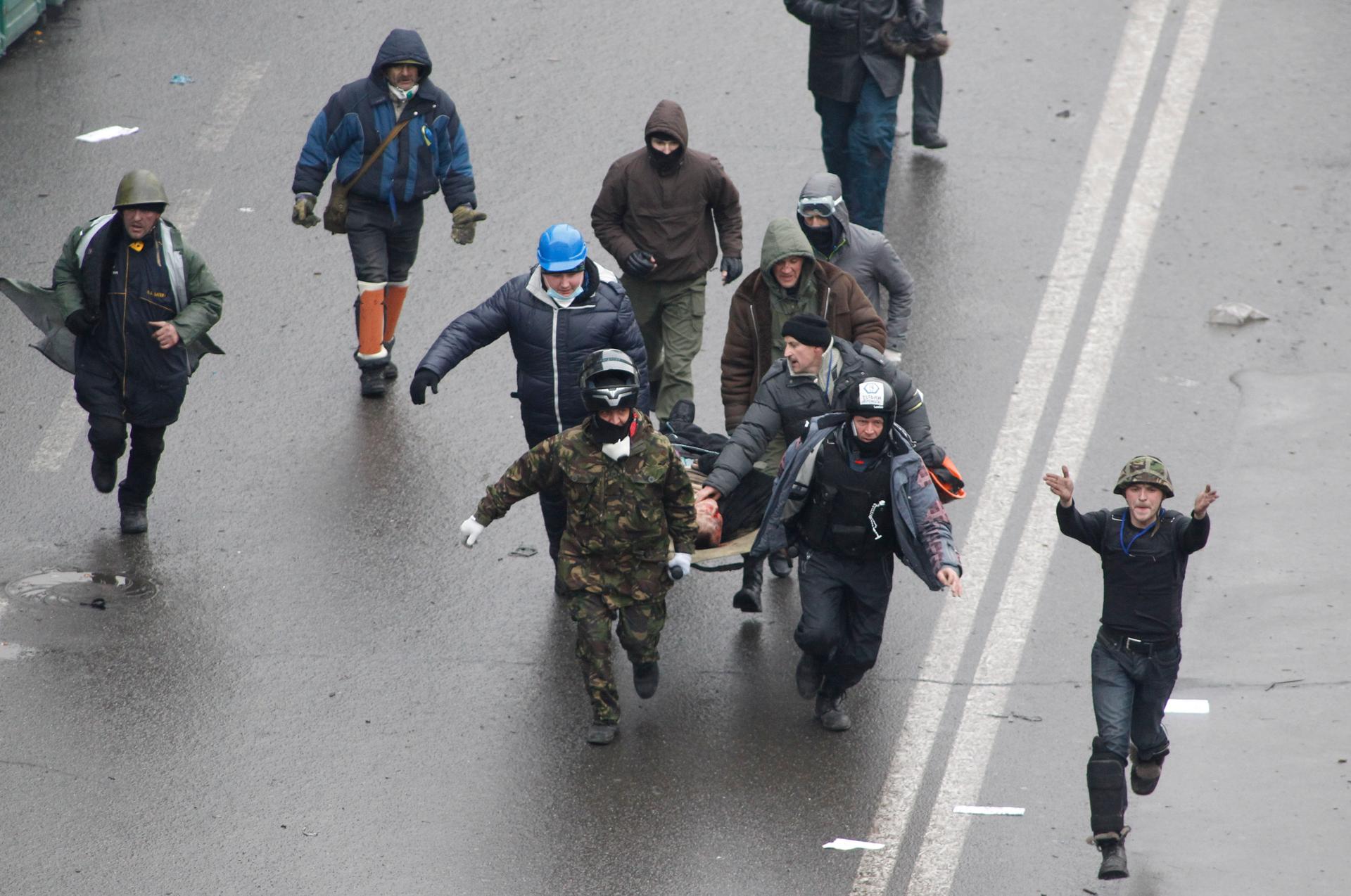 Anti-government protesters run with an injured man on a stretcher in downtown Kiev, February 20, 2014.  
