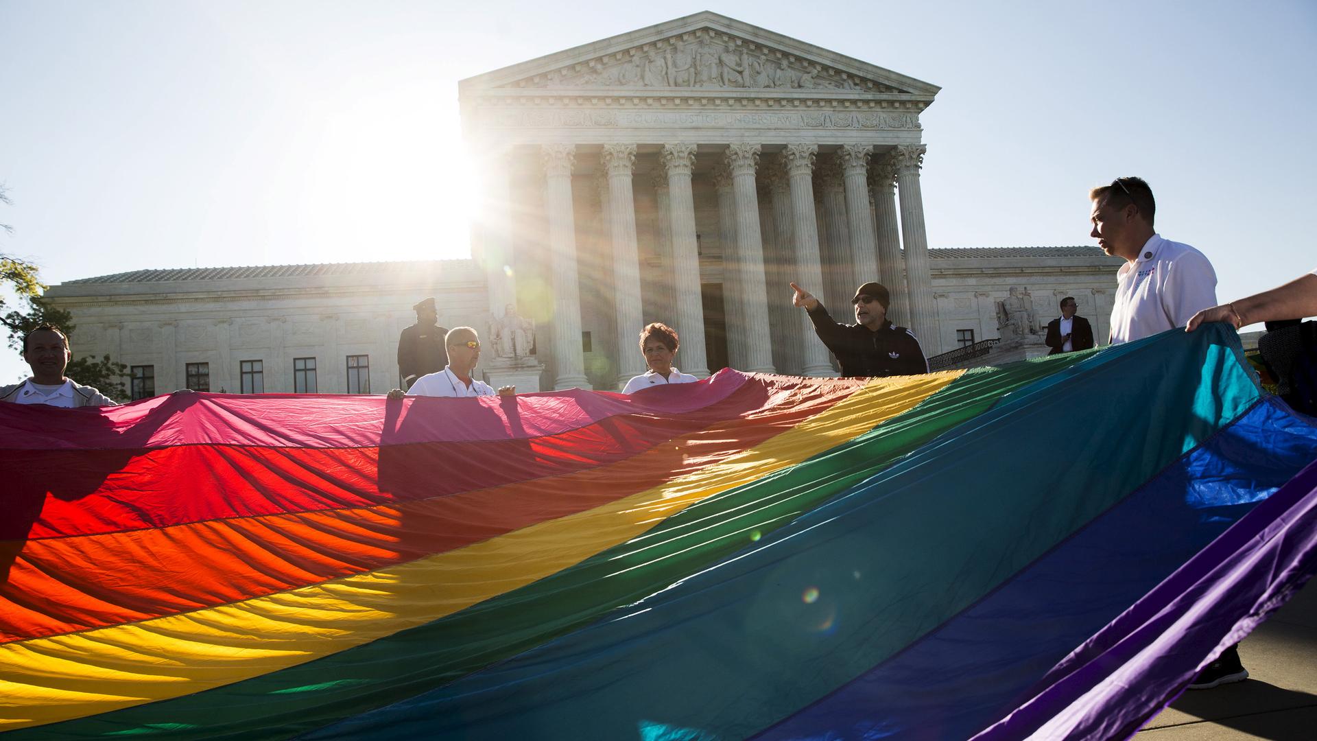 Gay marriage supporters hold a gay rights flag in front of the Supreme Court before a hearing about gay marriage on April 28, 2015.