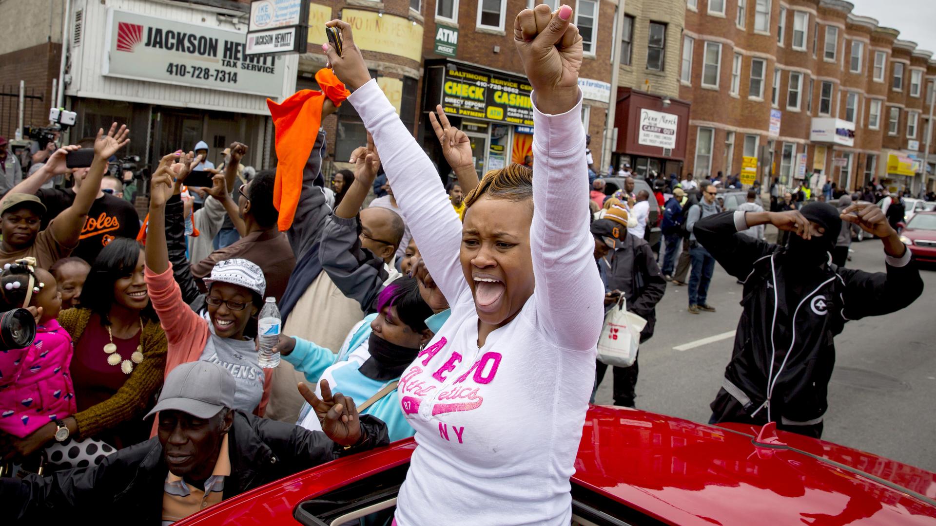 Baltimore residents gather at the corner North and Pennsylvania Avenues on May 1, 2015 to cheer the news that six police officer will face charges in the death of Freddie Gray.