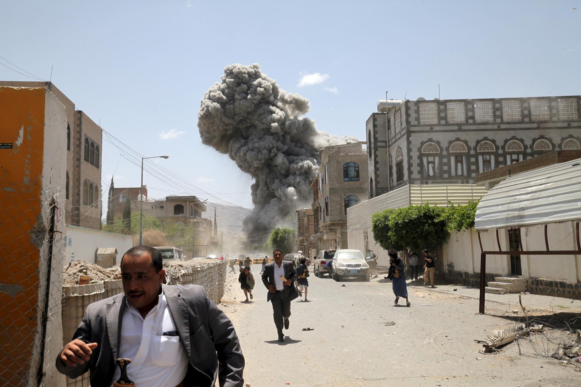People flee as smoke billows after air strikes hit the house of Yemen's former President Ali Abdullah Saleh in Sanaa May 10, 2015