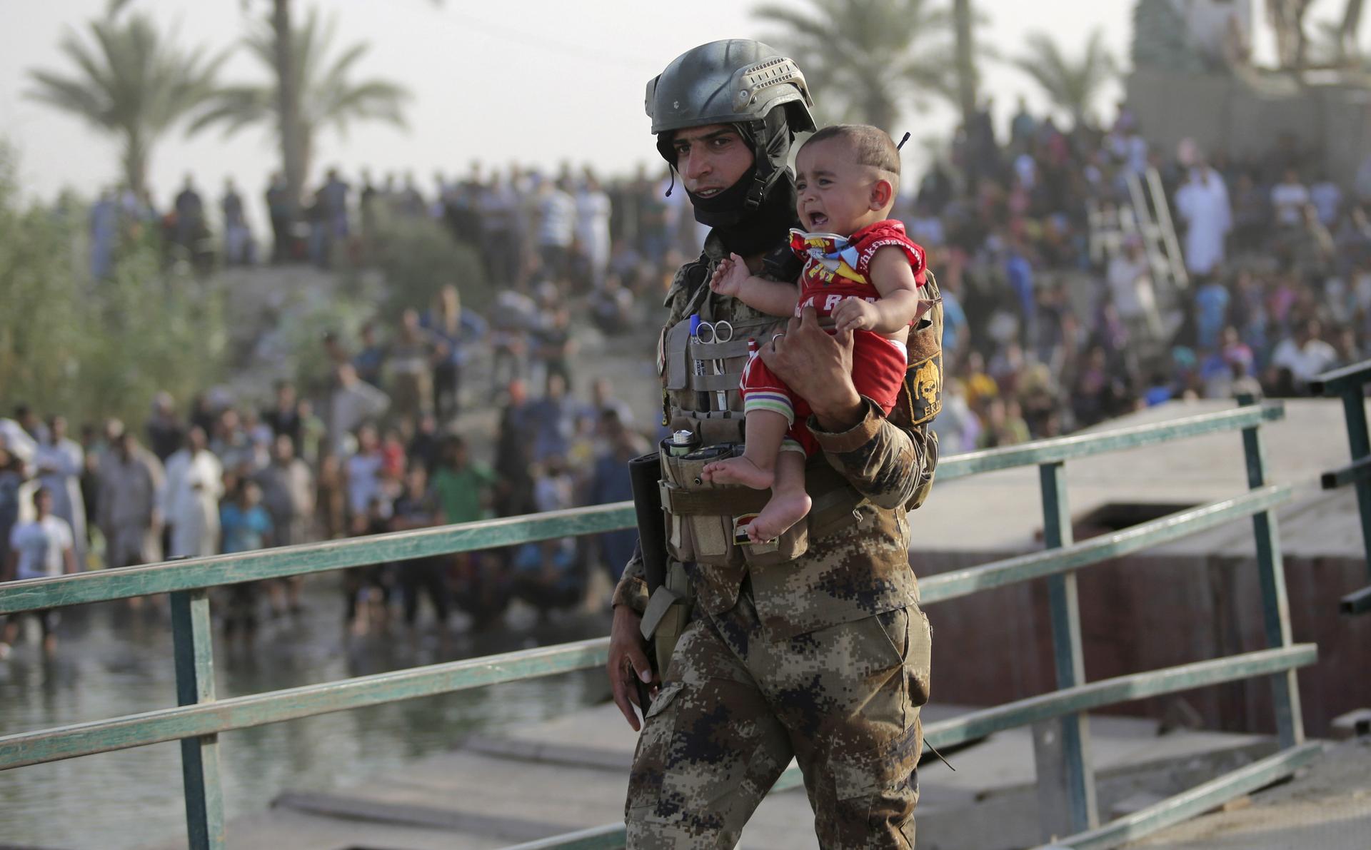 An Iraqi soldier carries a displaced child from Ramadi on the outskirts of Baghdad on May 19, 2015.