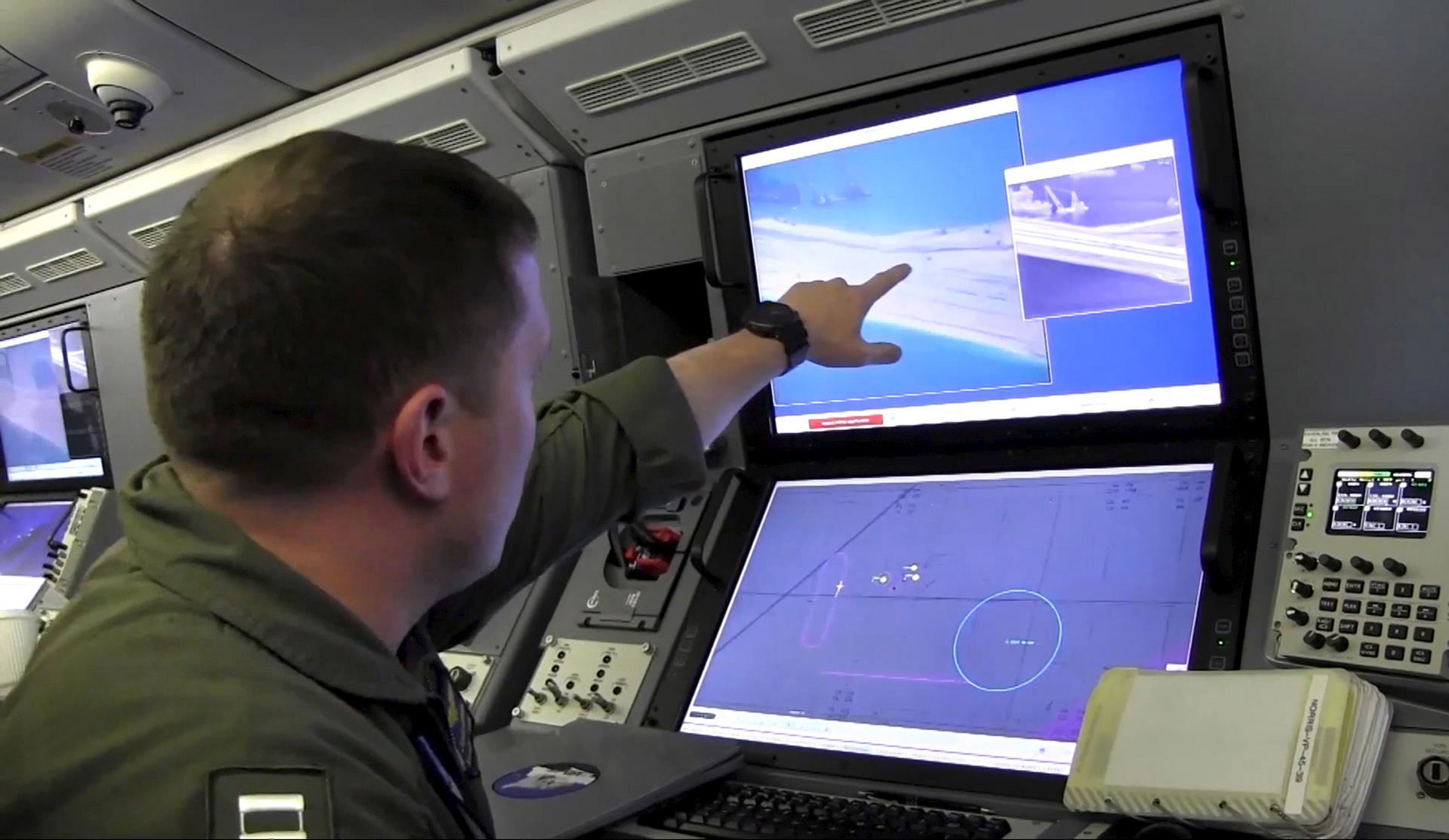A U.S. Navy crewman aboard a P-8A Poseidon surveillance aircraft views a computer screen purportedly showing Chinese construction on the reclaimed land of Fiery Cross Reef in the disputed Spratly Islands in the South China Sea in this still image from vid