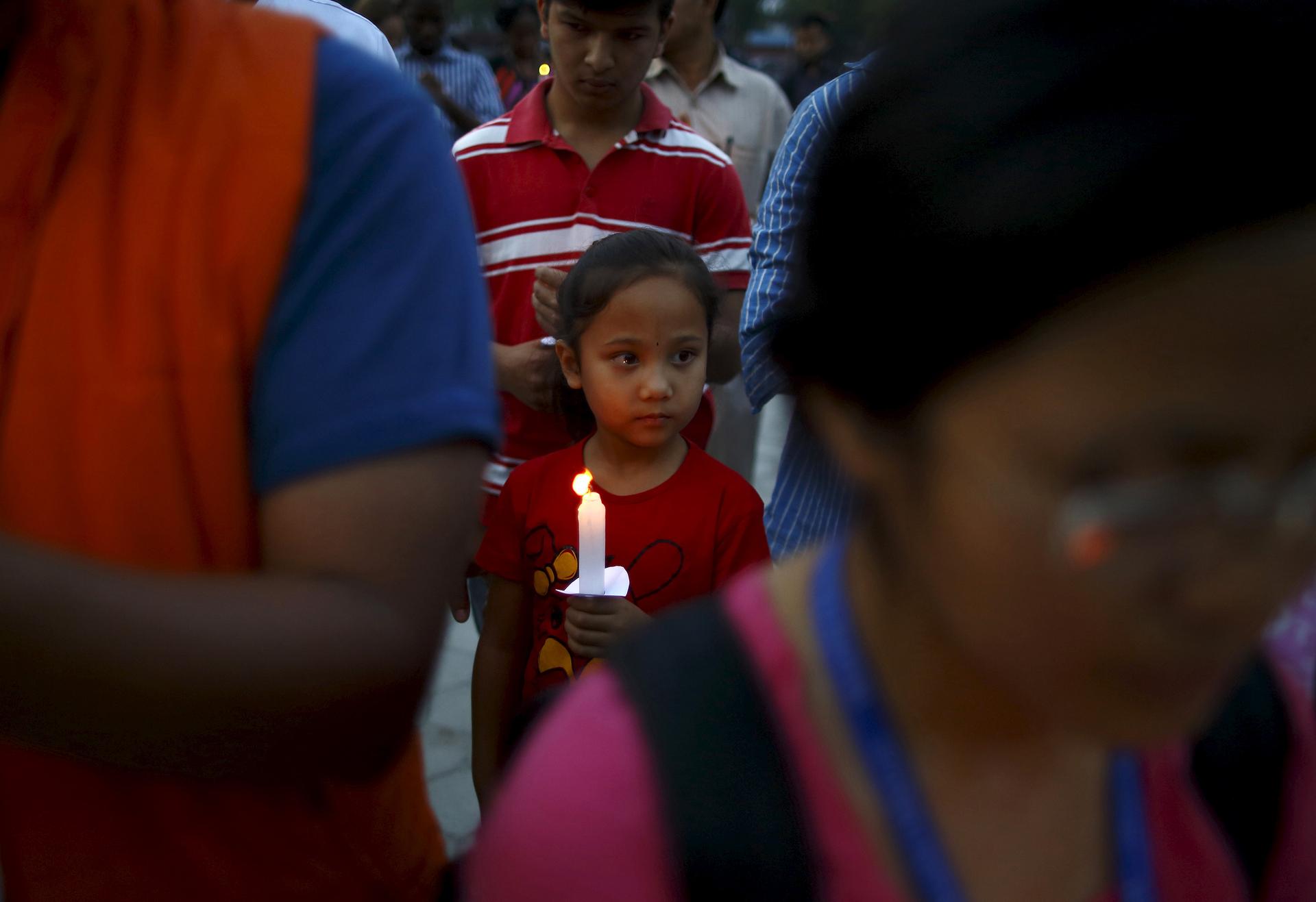A girl holding a candle takes part in a candlelight vigil, a month after the April 25 earthquake, in Kathmandu, Nepal May 25, 2015.