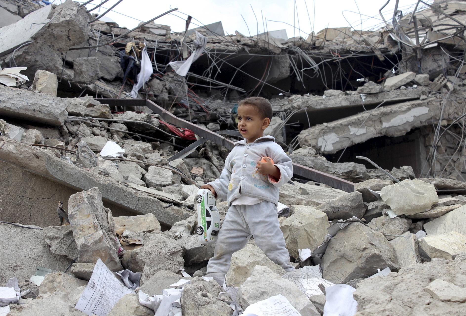  boy walks as he collects toys from the rubble of a house destroyed by a recent air strike in Yemen's northwestern city of Saada