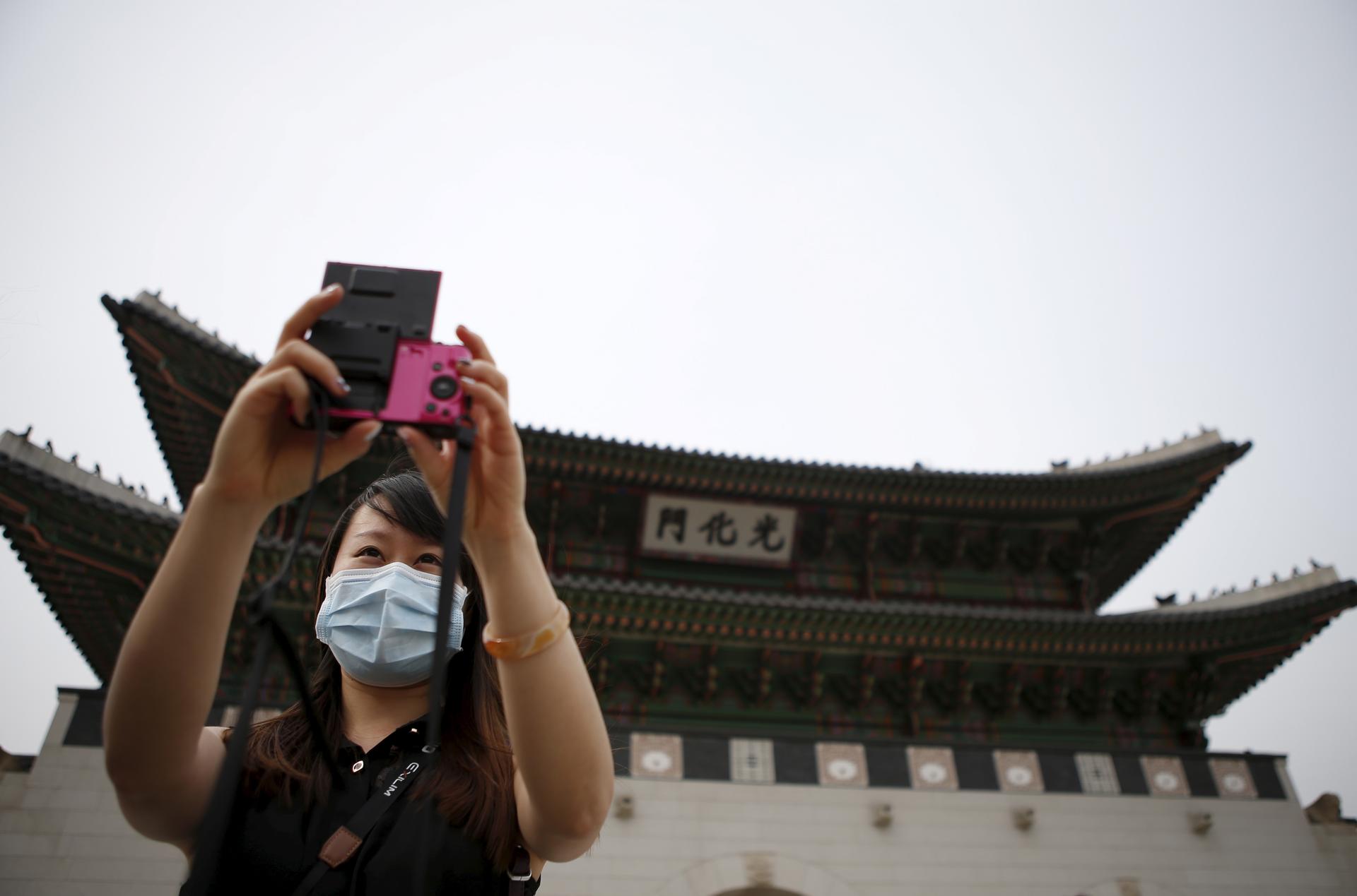 Chinese tourist wearing a mask to prevent contracting Middle East Respiratory Syndrome (MERS) takes a selfie in front of the main entrance of the Gyeongbok Palace in central Seoul, South Korea on June 4, 2015.