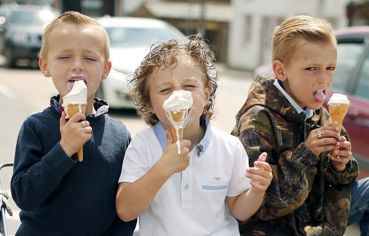 Children eat ice cream that's melting fast at the annual horse fair Appleby-in-Westmorland, Britain.