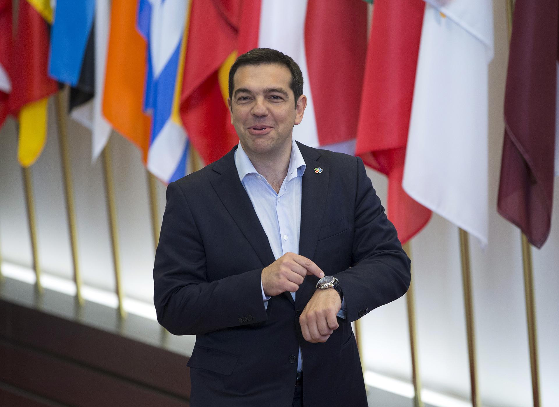 Greek Prime Minister Alexis Tsipras shows his watch while leaving the European Council headquarters on the first day of an EU-CELAC Latin America summit in Brussels, Belgium June 11, 2015.